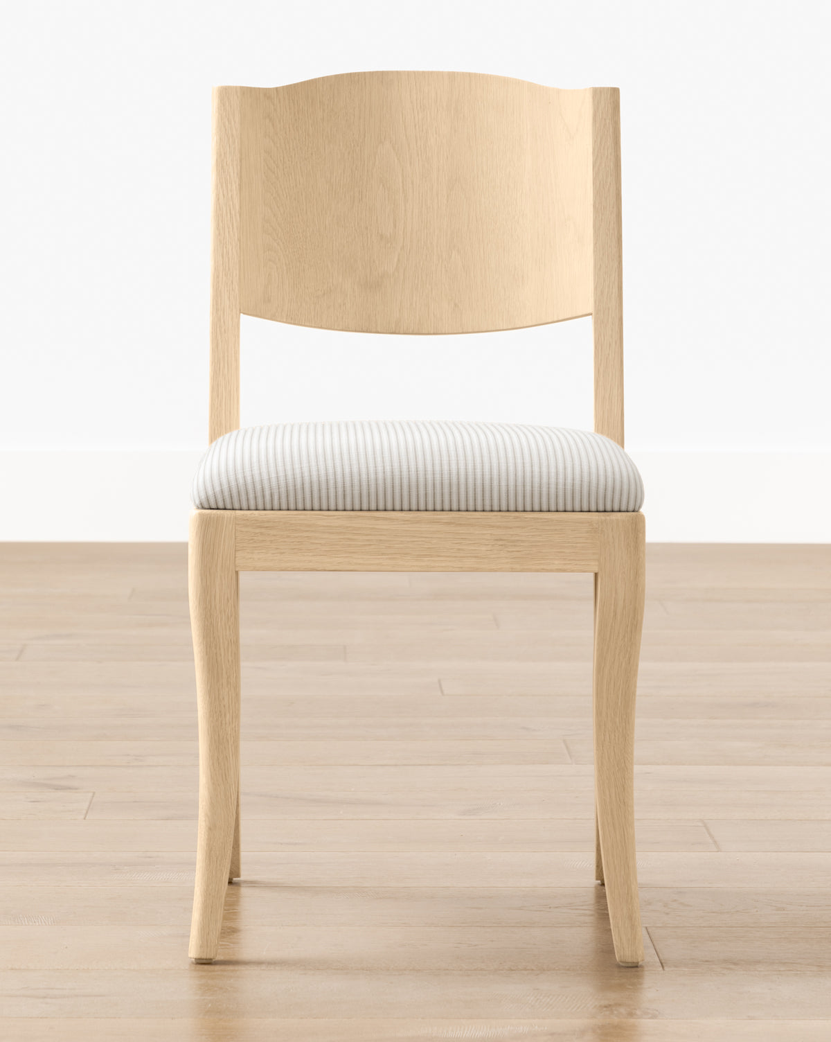 The Shepherd Dining Chair has a light wood, white oak frame with a curved backrest and an upholstered seat in light gray and white stripes, shown on a wooden floor with a white wall by McGee & Co.
