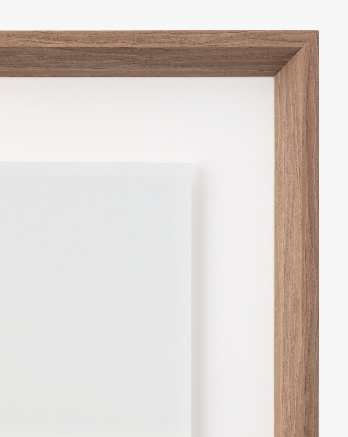 Close-up of the top right corner of a natural wood frame with a white mat, featuring wall art titled Shimmer of Wave with a partially visible, light-colored artwork inside.