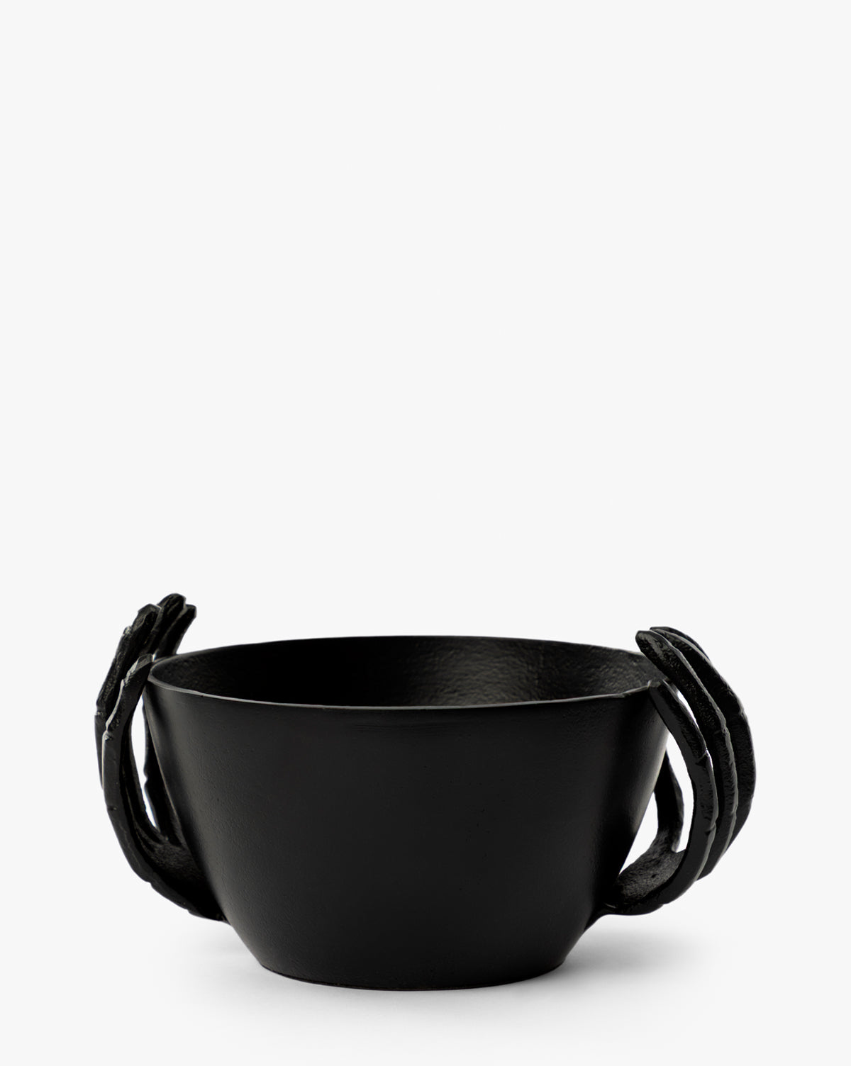 The Skeleton Hands Treat Bowl features two matte black sculpted hands on either side, creating a sleek, artistic look perfect for serving Halloween candy. Seen against a plain white background, it’s an eye-catching party centerpiece by McGee & Co.