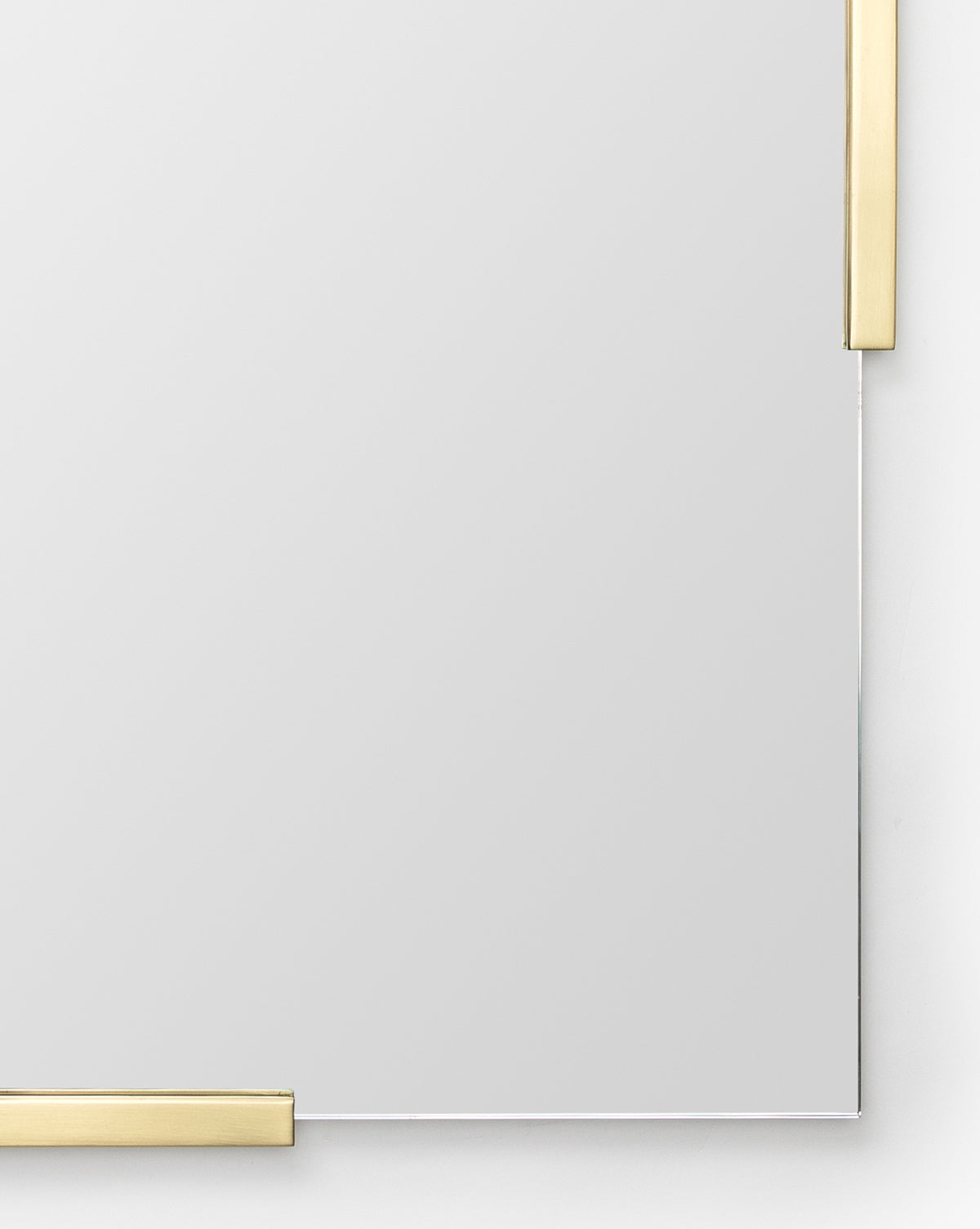 The Slade Mirror is a rectangular, frameless modern mirror with a white background and clear surface. It features minimalist thin gold metallic accents on the top right and bottom left corners for an elegant touch, by McGee & Co.