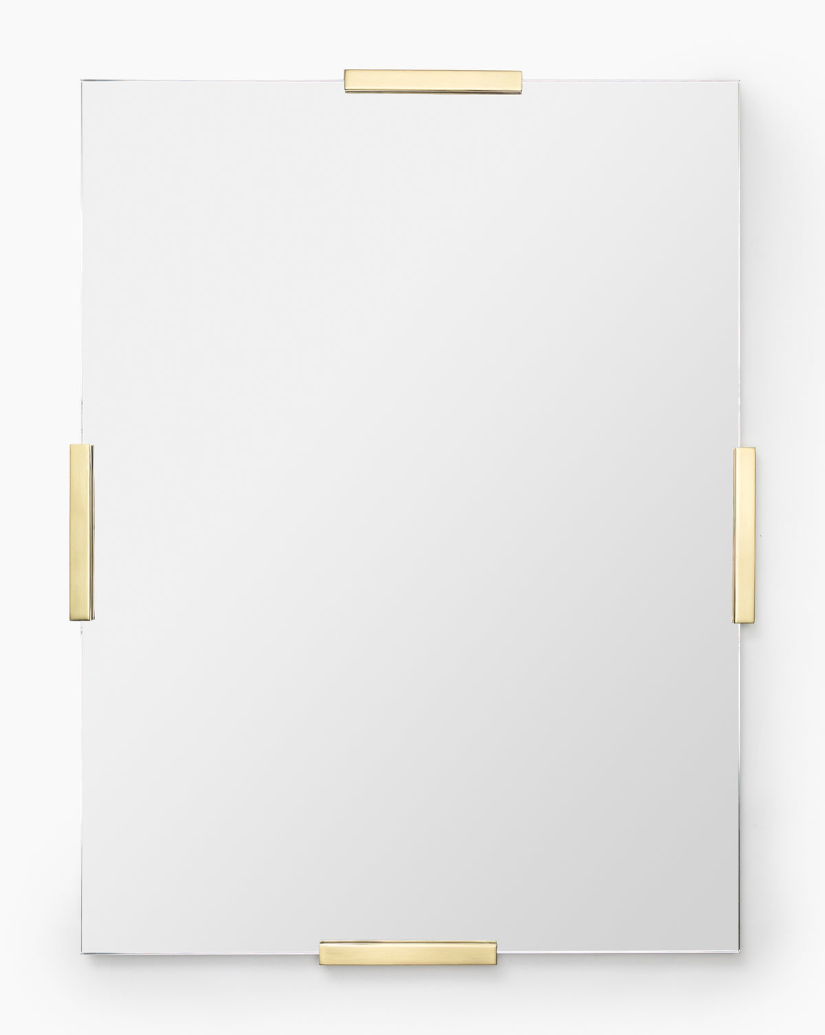 The Slade Mirror is a rectangular frameless mirror secured by four gold metal brackets on each side, creating a sleek modern look against a plain white background, by McGee & Co.