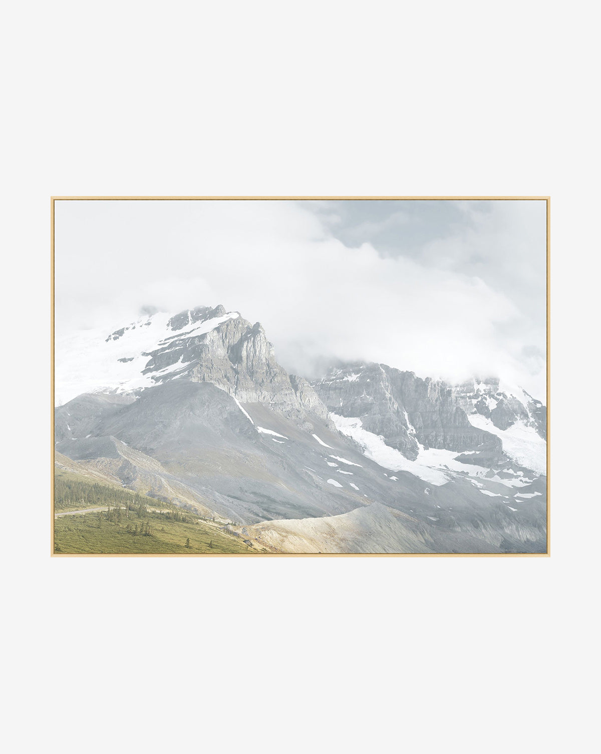 Snow Covered Peaks: A scenic landscape featuring snowy mountains partly veiled by clouds, rocky slopes, and grassy foreground, framed with a thin light border—ideal photographic wall art to enhance any space.