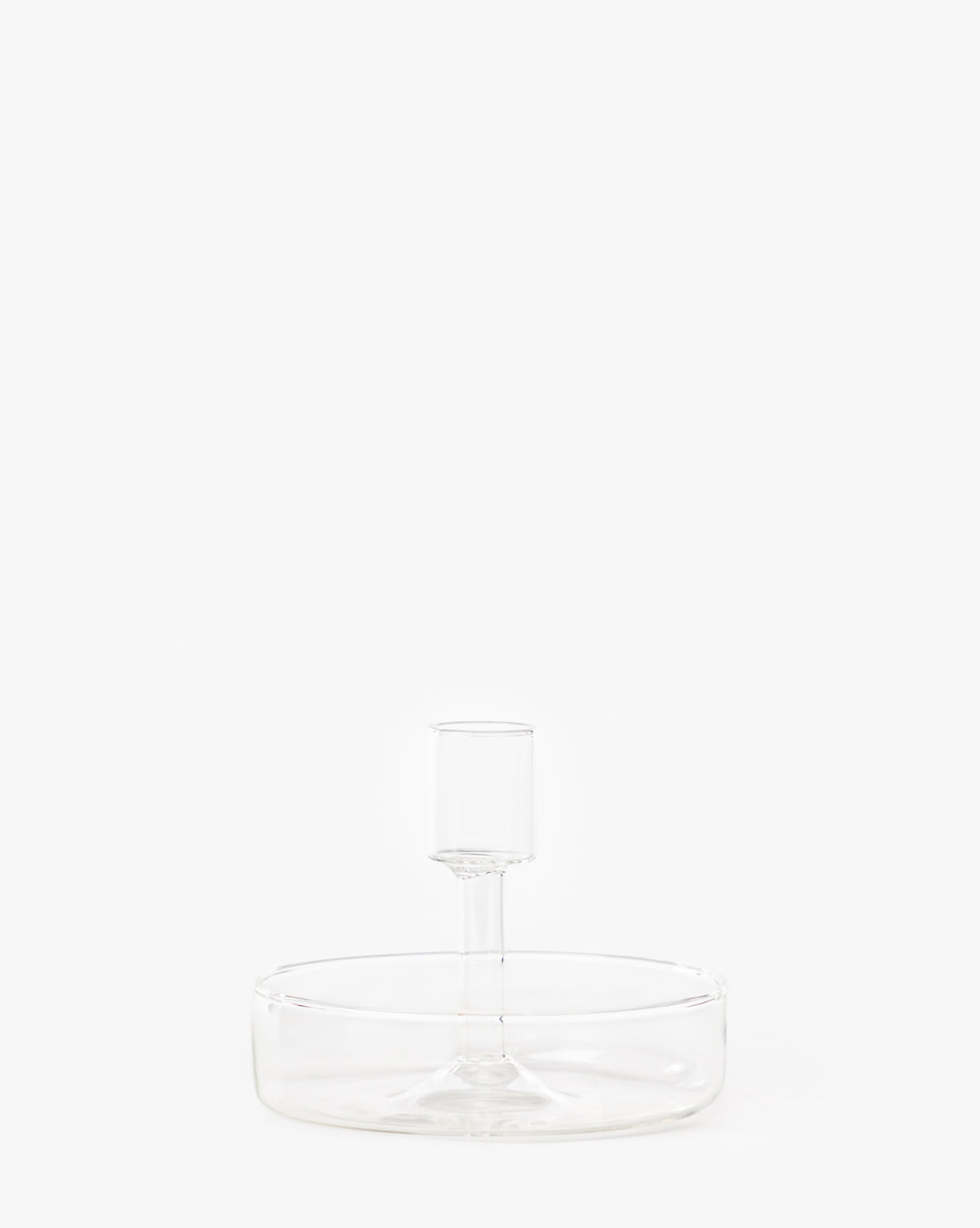 The Sofia Candle Holder is a clear glass serving dish with a wide, shallow base and central raised holder, ideal for displaying taper candles. Photographed against a plain white background.