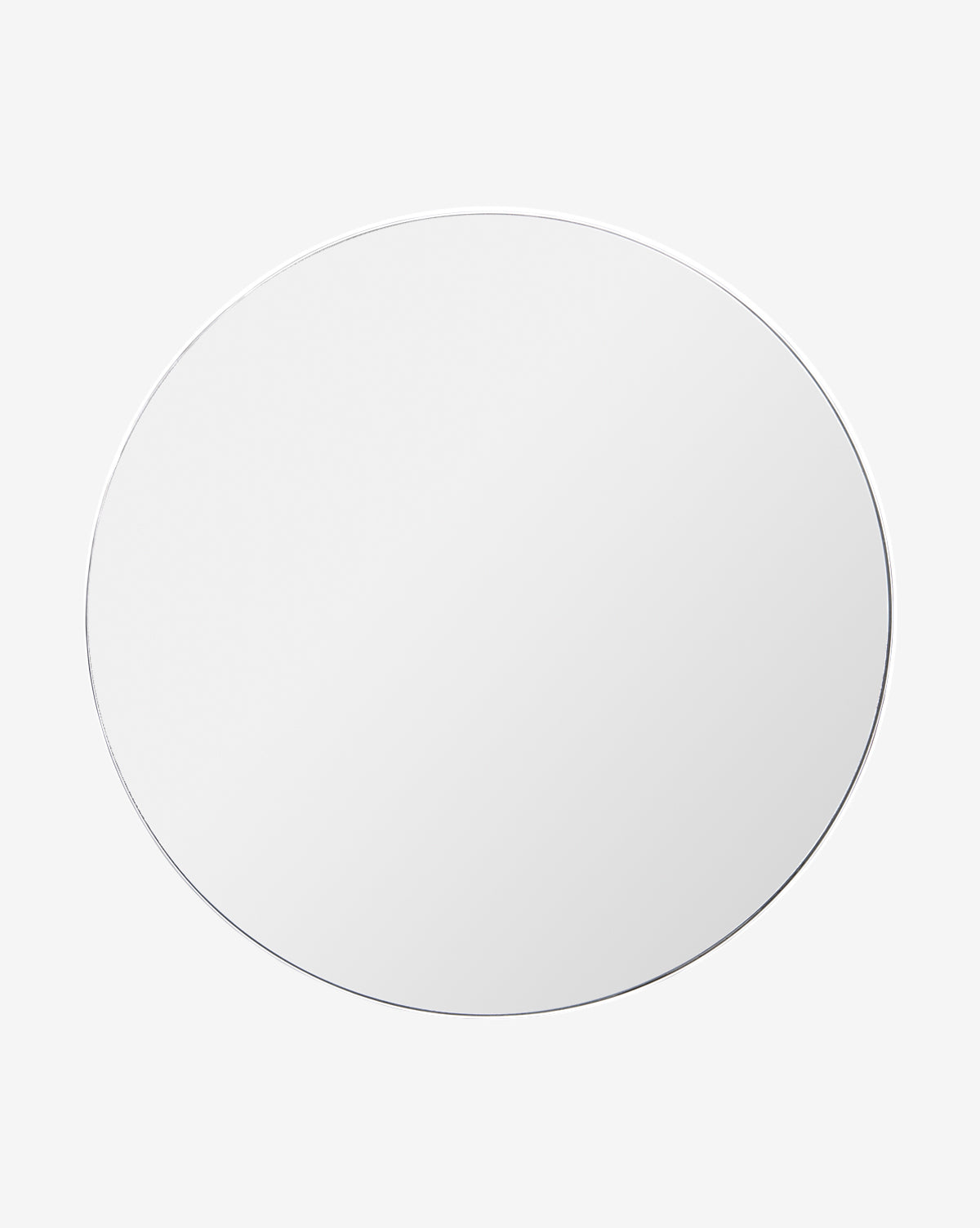 The Solange Mirror, featuring a large round design with a thin stainless steel frame, is centered against a plain light gray background. Its minimalist surface reflects only light and reveals no objects or scenery by McGee & Co.