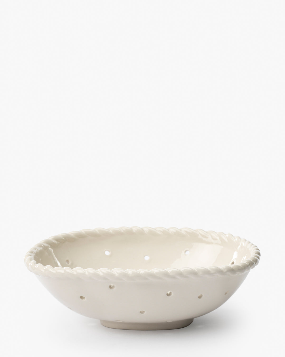 The Solene Stoneware Bowl, featuring a twisted rope rim and drainage holes on its white ceramic surface, is perfect for kitchen decor. Displayed against a plain white background.