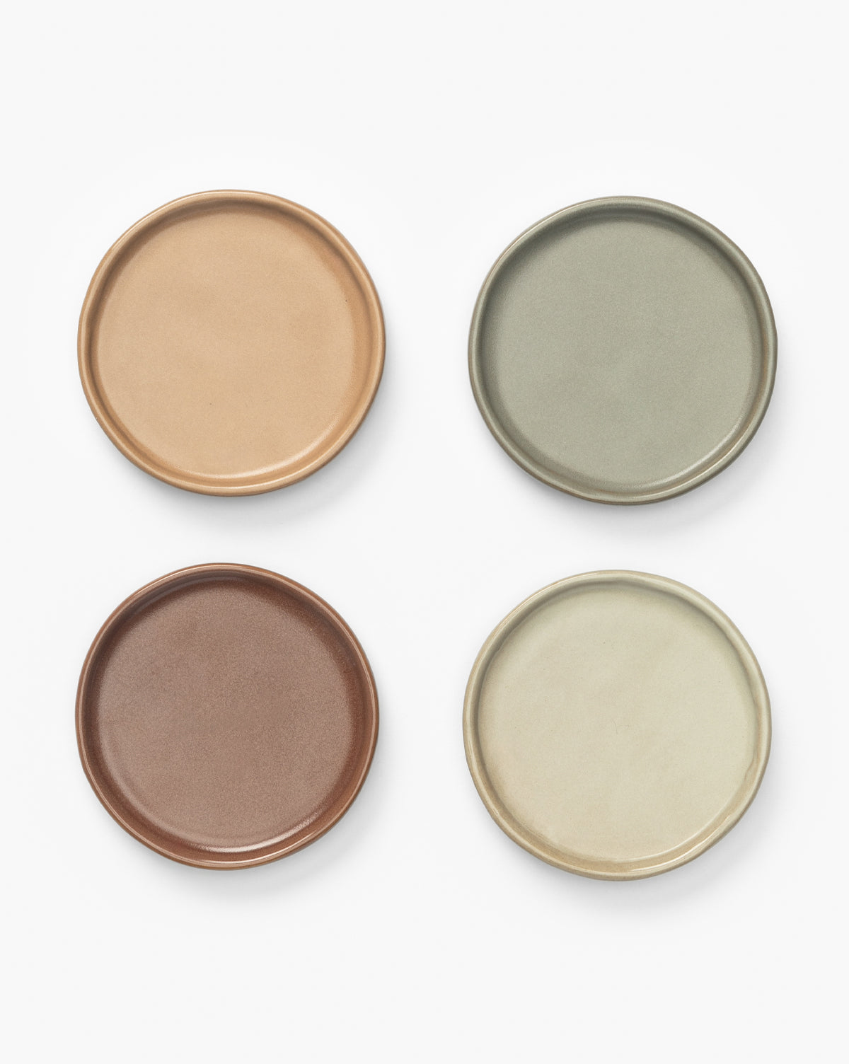 The Speckled Ceramic Coasters (Set of 4) features round coasters in light brown, sage green, reddish-brown, and beige—ideal earthy tones for stylish tabletop decor, by McGee & Co.