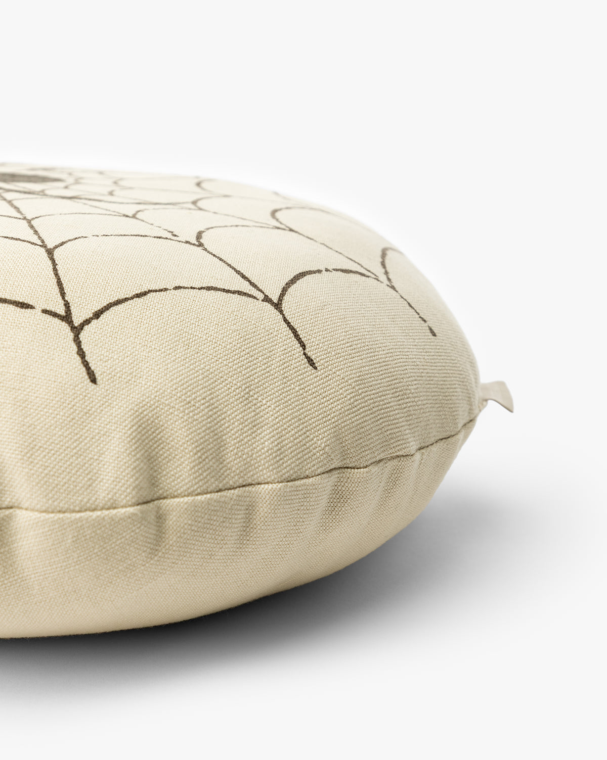 The Spider Pillow is a round, beige cushion with a simple black geometric line design—ideal as a subtle Halloween accent, by McGee & Co.