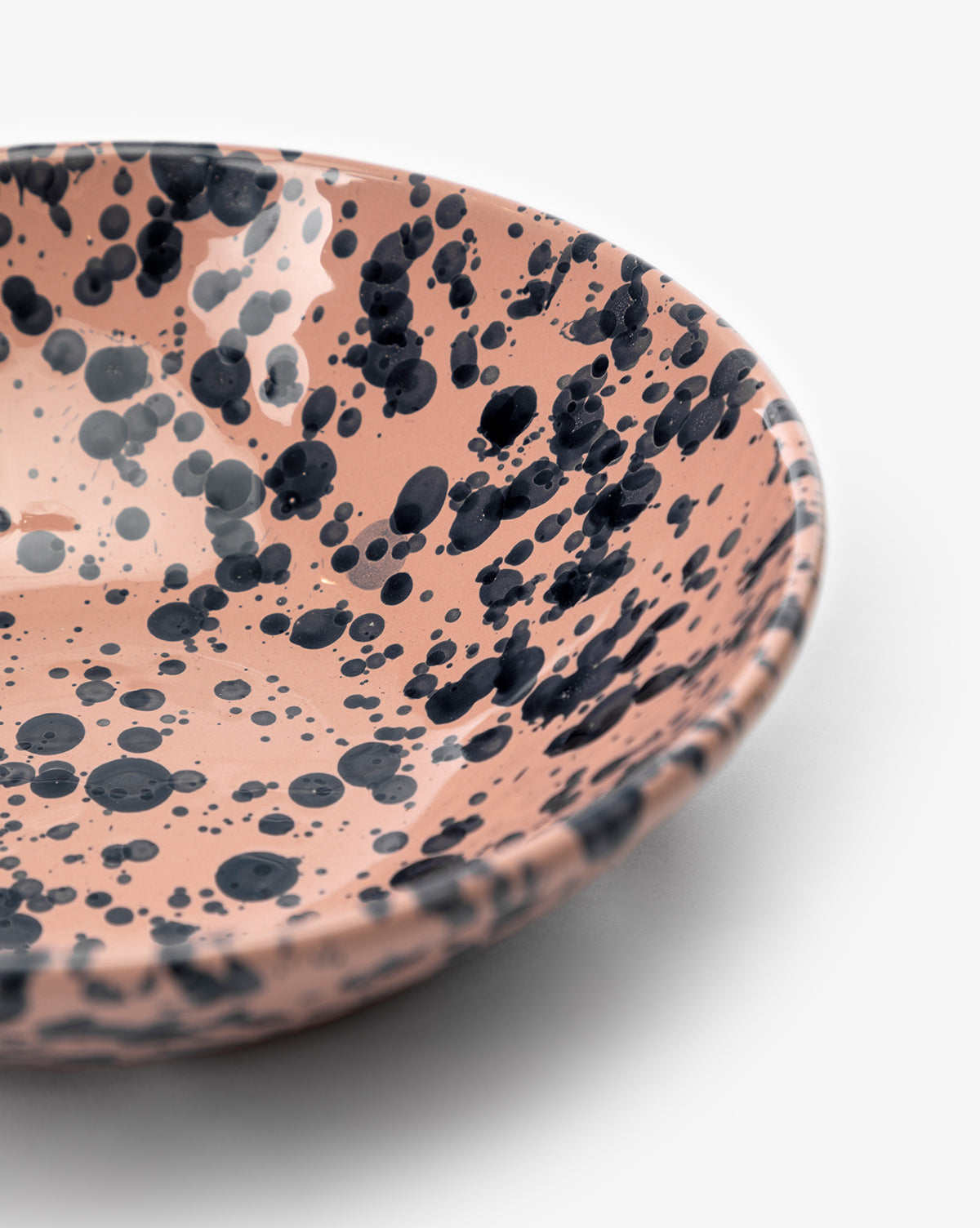 Close-up of the Splatter Large Bowl, an artisan ceramic piece with a pink base and unique black splatter spots, displayed on a white background, by McGee & Co.