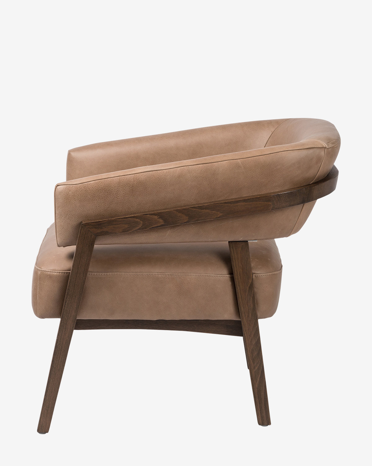 Side view of the Stanley Lounge Chair in tan leather with a curved backrest and angled dark brown wooden legs, showcasing contemporary design against a plain white background, by McGee & Co.