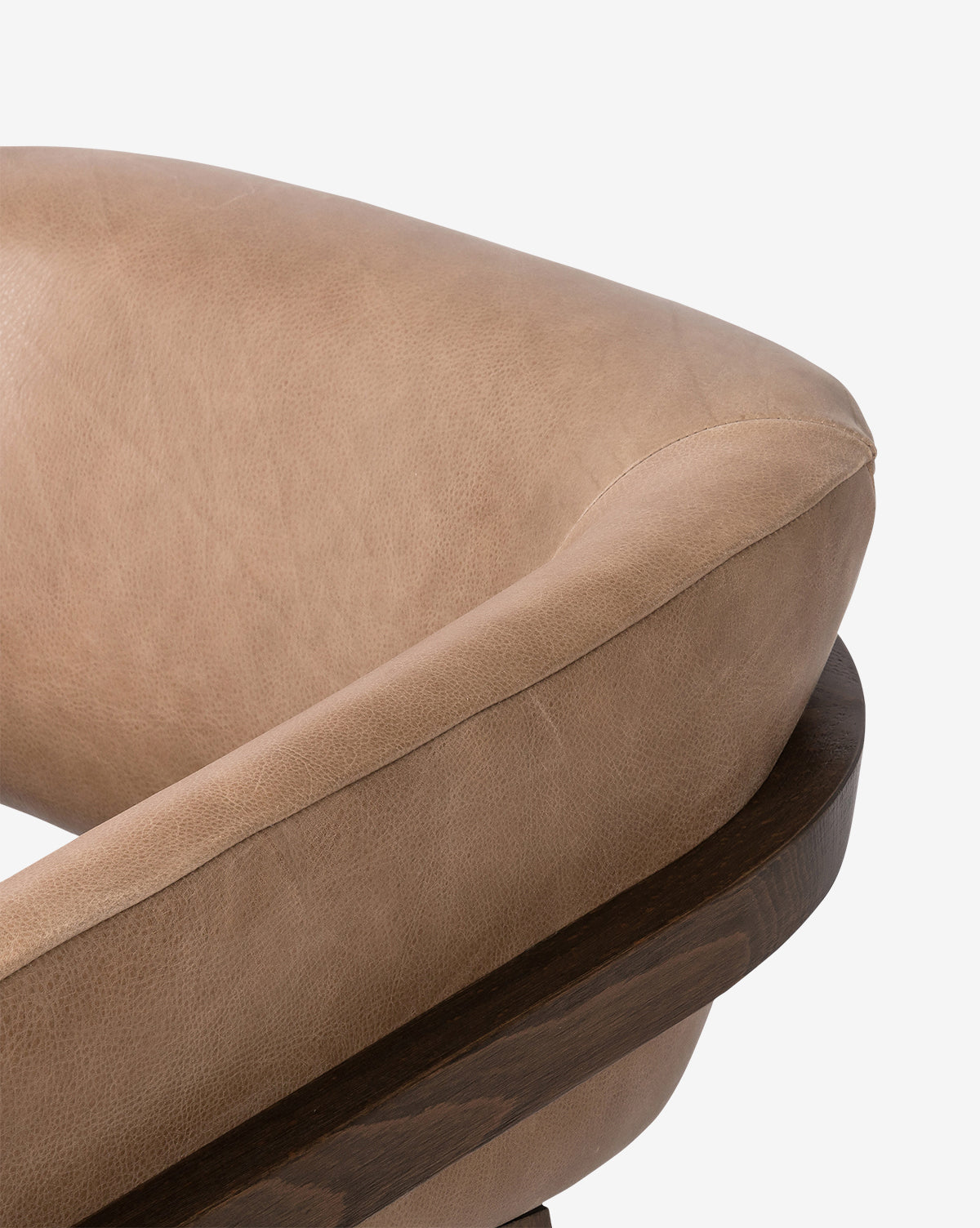 Close-up of the Stanley Lounge Chair, upholstered in light brown leather with curved padding and a dark wooden frame, set against a plain white background for a contemporary look, by McGee & Co.