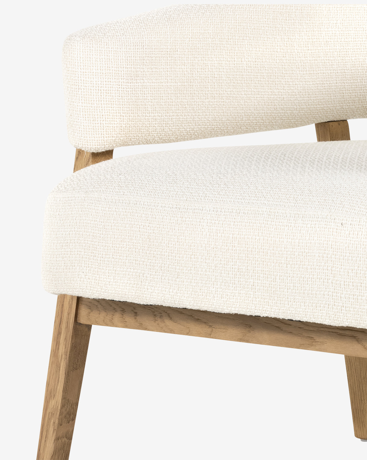 Close-up of the Stanley Lounge Chair, featuring a textured off-white upholstered seat and backrest, with light wooden legs and frame. This contemporary design is set against a plain, light background, by McGee & Co.
