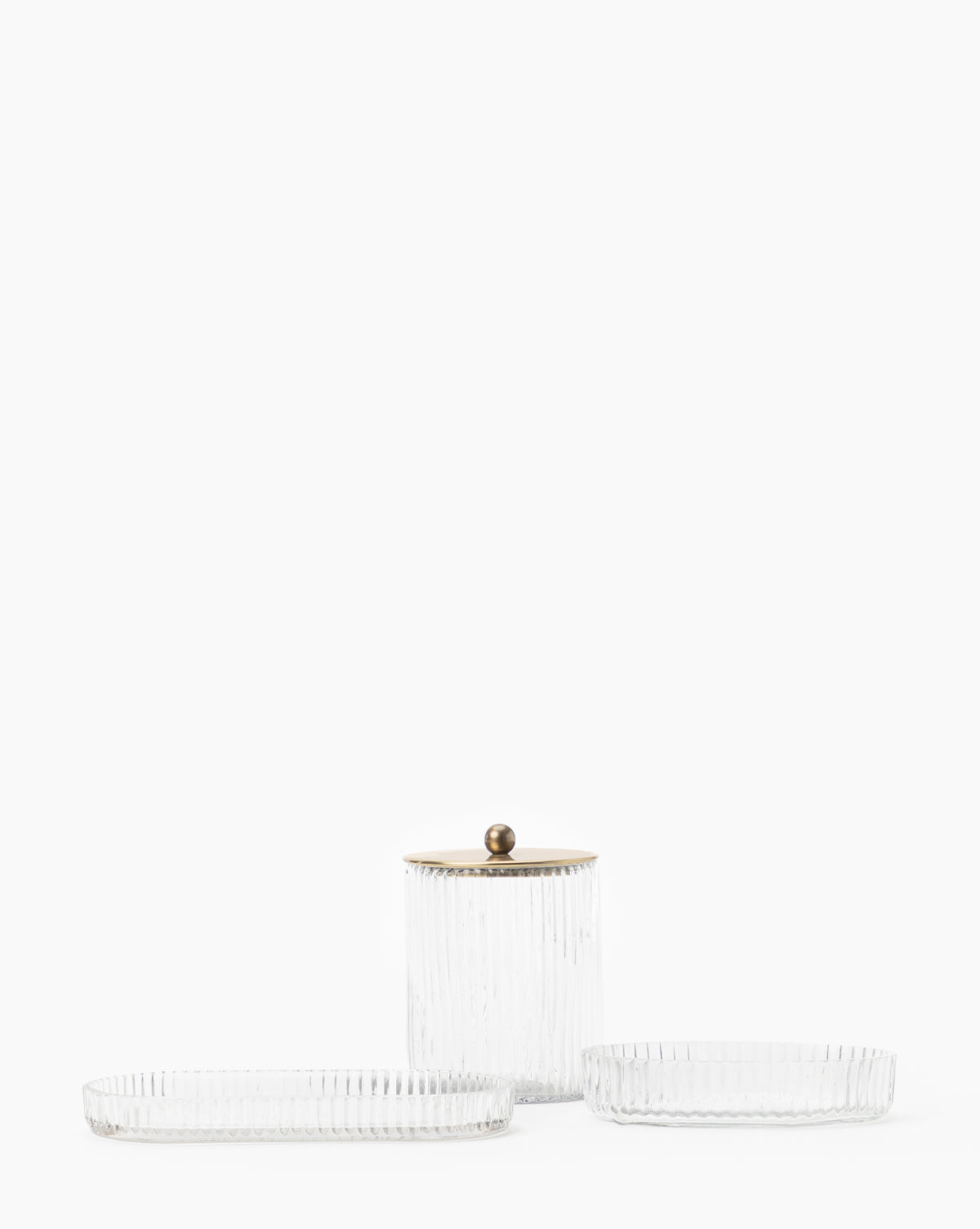 Three clear, ribbed blown glass pieces from the Stein Glass Collection—two shallow trays and one taller jar with a metallic lid and round handle—are displayed on a white background, ideal for organizing your bathroom countertop.