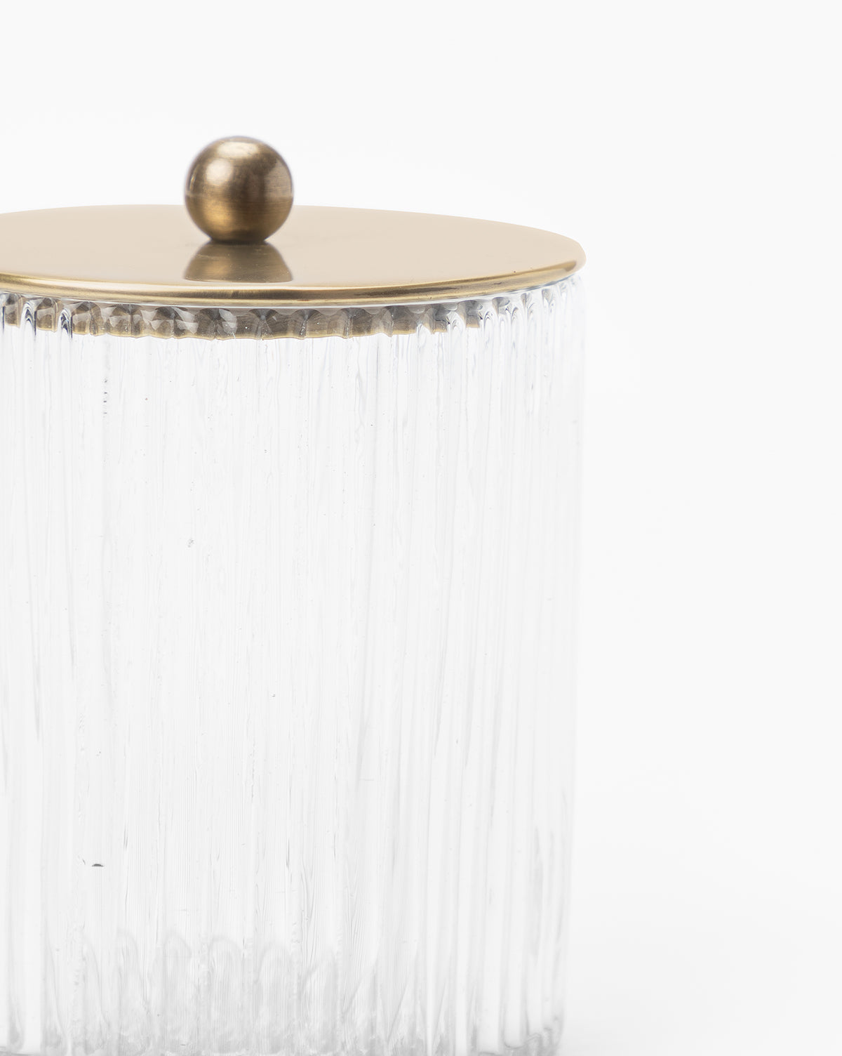 A clear, ribbed blown glass jar with a round gold-colored metal lid and knob from the Stein Glass Collection, ideal for display on a bathroom countertop against a plain white background.