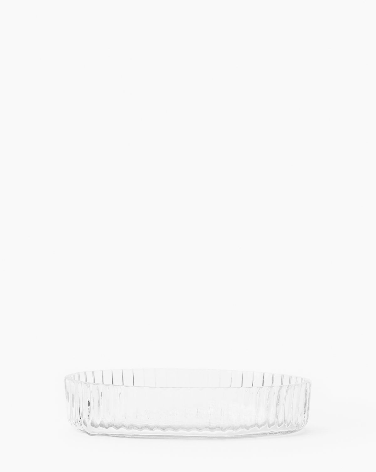 The Stein Glass Collection features a clear, empty, round blown glass dish with ribbed sides, set against a white background—an elegant addition to any bathroom countertop.