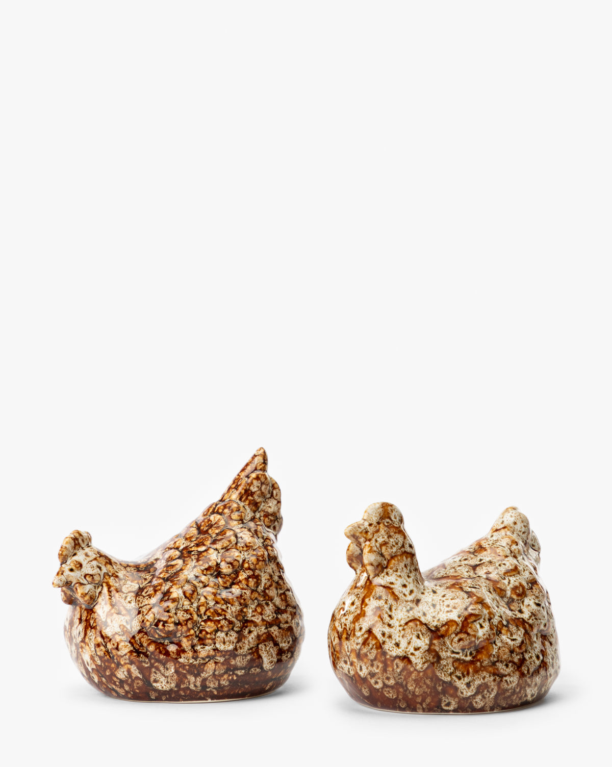 The Stoneware Hens (Set of 2) feature an artisanal speckled brown and cream glaze, adding rustic charm to any decor, by McGee & Co. Displayed side by side on a plain white background.