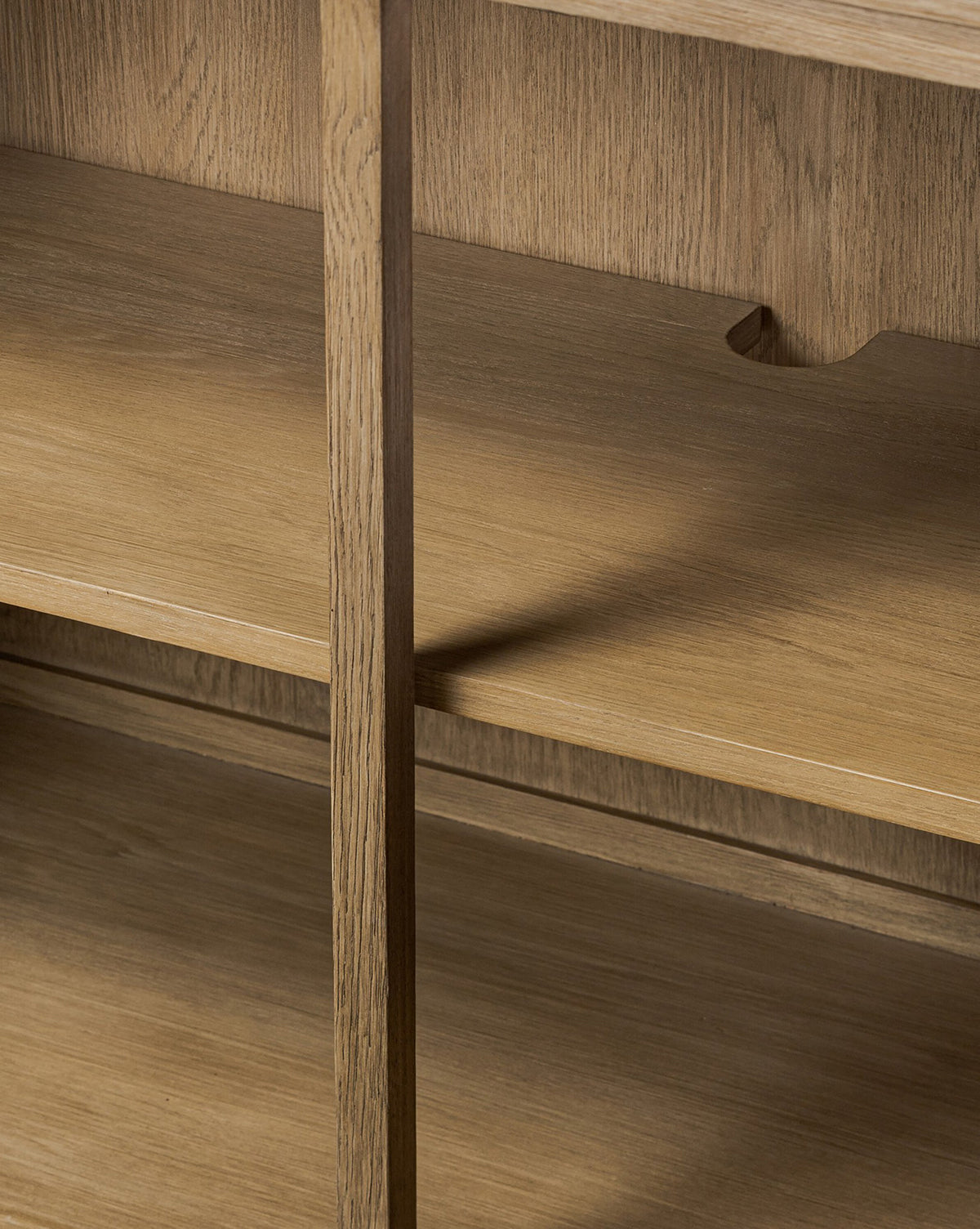 Close-up of the Stonington Oak Sideboard’s wooden shelves with a vertical divider and back cutout notch, highlighting the grain and texture of weathered washed oak—a perfect vintage-inspired detail, by McGee & Co.