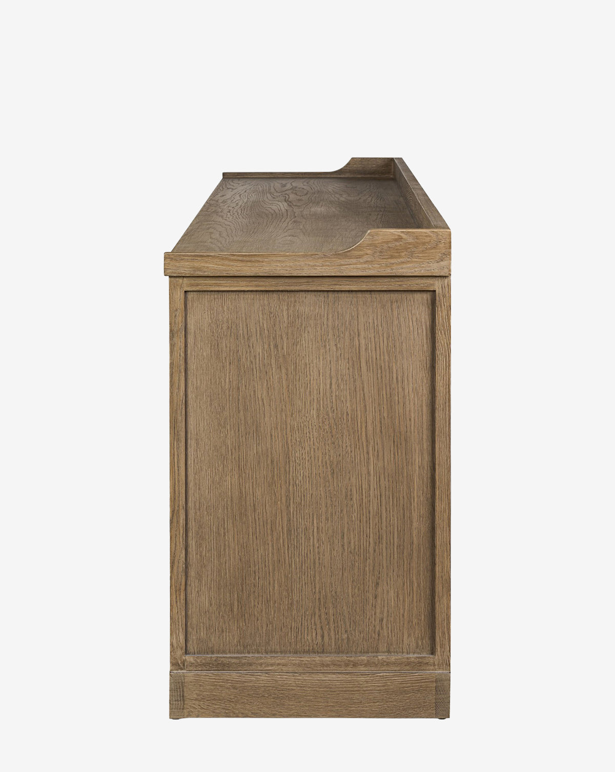 A side view of the Stonington Oak Sideboard shows its natural finish, flat panel, and raised top edges. The weathered washed oak and visible wood grain bring a simple, modern touch to this vintage-inspired sideboard, by McGee & Co.