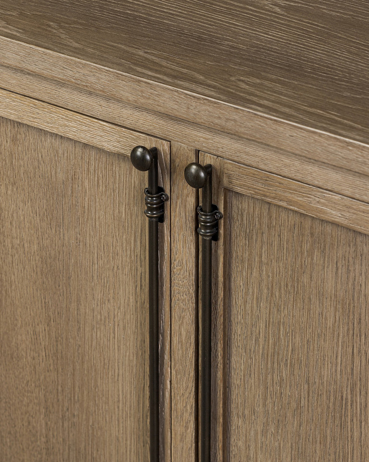 Close-up of two cabinet doors on the Stonington Oak Sideboard, featuring long vertical dark bronze handles and top round knobs. The weathered washed oak showcases a natural light brown grain and vintage-inspired texture, by McGee & Co.