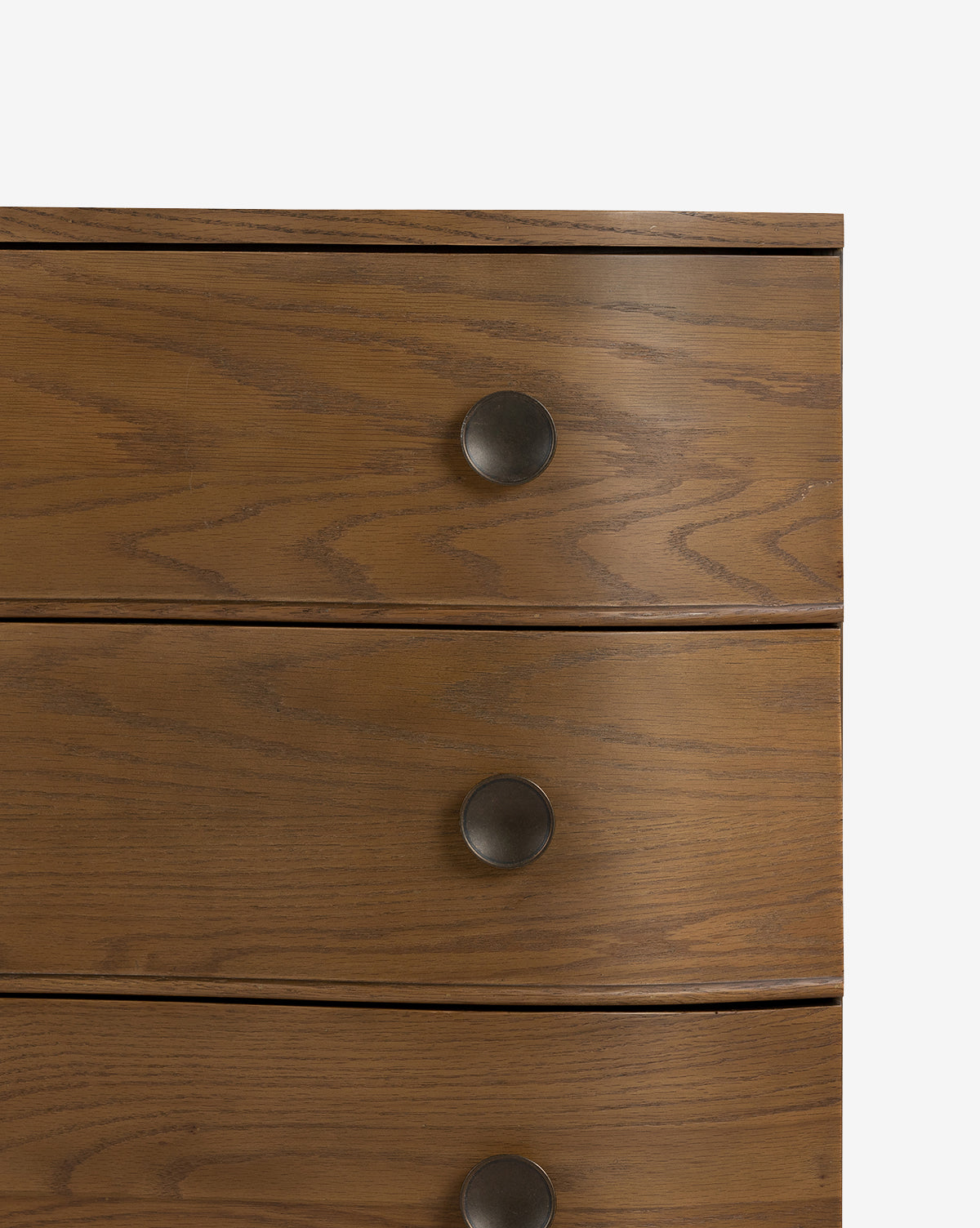 Close-up of the Strasburg Nightstand, a wooden dresser with a natural finish and three drawers. Each drawer features a round, dark metal knob handle. Perfect for bedroom styling and resembles an antique nightstand, by McGee & Co.