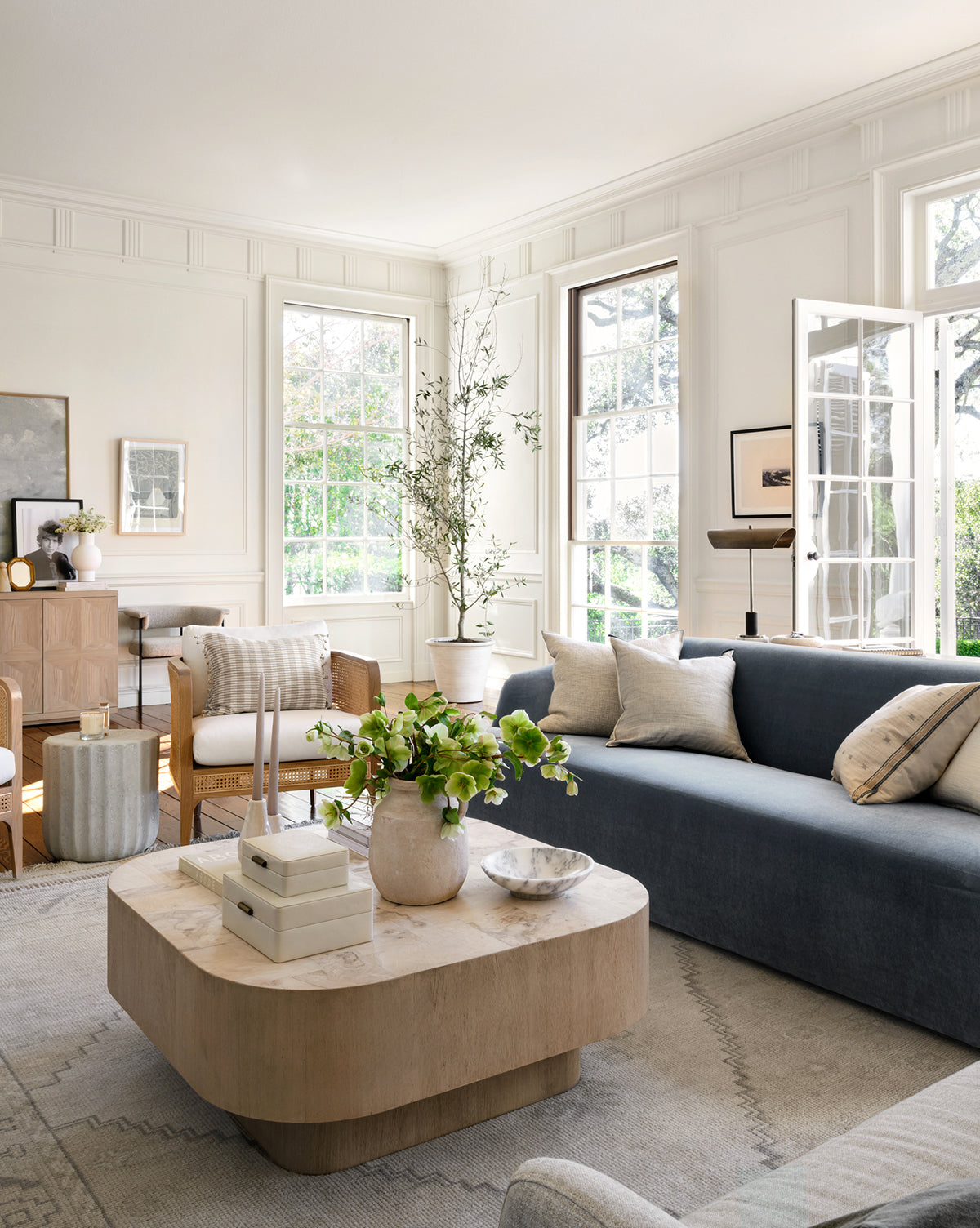 The Pembroke Hand-Knotted Wool Rug grounds the modern minimalist space with sunlight, books, a vase, and greenery accents, by McGee & Co.