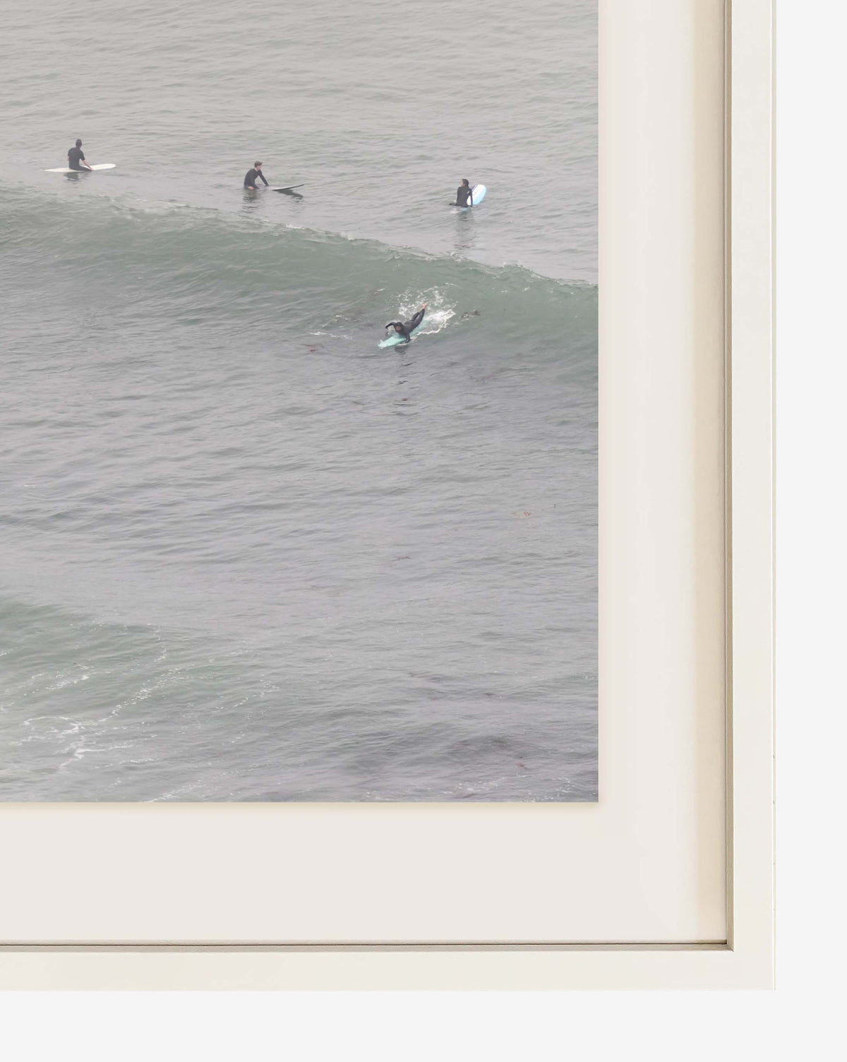 The original photograph Surf Rider shows four surfers in wetsuits on their boards as one catches a small wave. Beautifully framed with a cream mat and frame, its a museum-grade piece perfect for any wall.