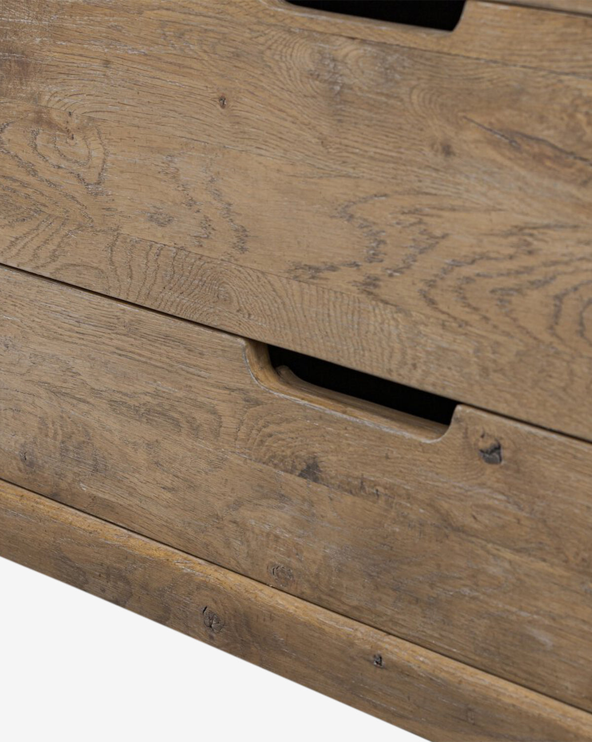 Close-up of the Sutton Trunk dresser in weathered oak, featuring two storage drawers with rectangular cut-out handles and a natural, rustic finish that highlights visible wood grain patterns, by McGee & Co.