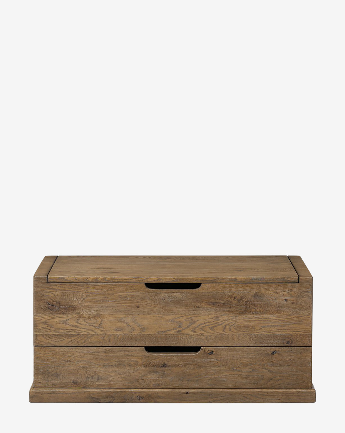 The Sutton Trunk is a rectangular wooden chest with a rustic weathered oak finish, two front drawers with cut-out handles, and a flat base. It is shown against a plain white background, by McGee & Co.