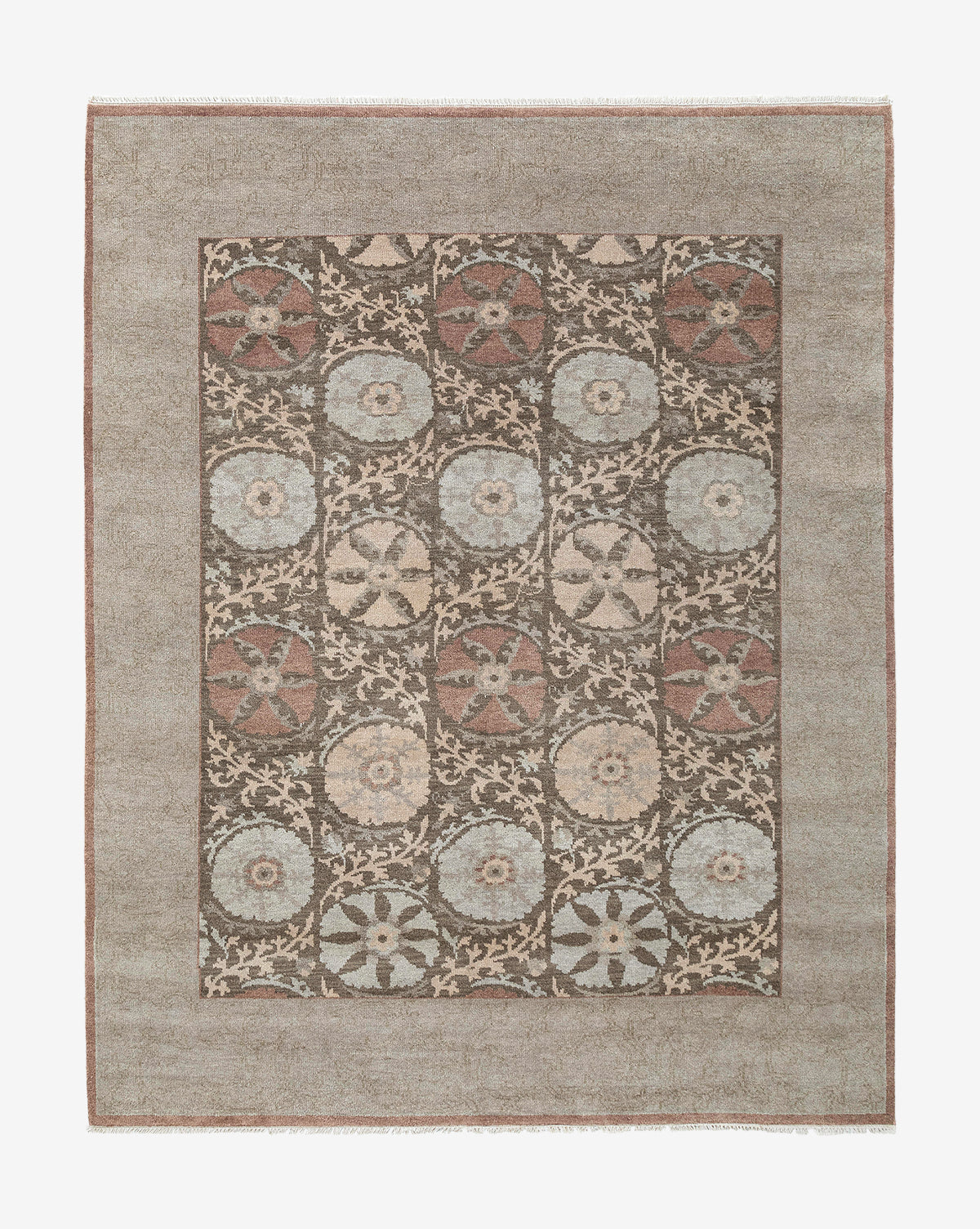 The Suzani Hand-Knotted Wool Rug is a rectangular handmade piece with a muted brown border and a grid of circular floral motifs in soft blue, beige, and rust on a dark background by McGee & Co.
