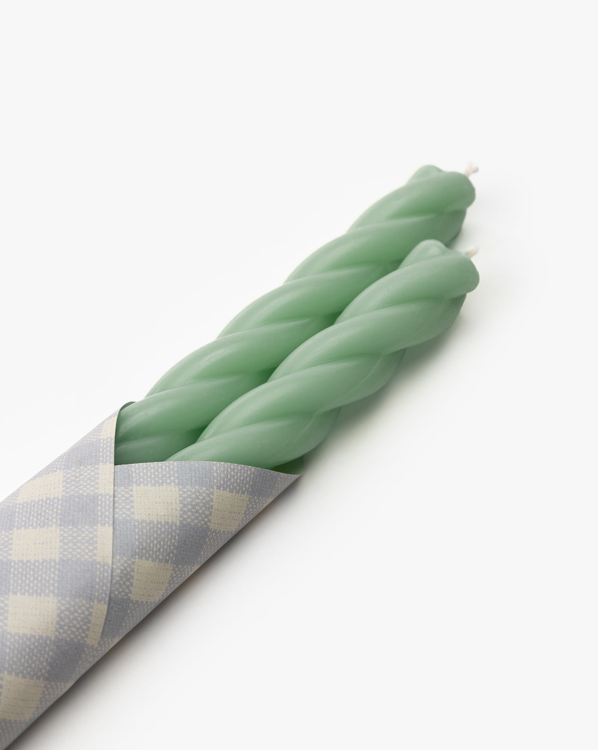 The McGee & Co. x Loeffler Randall Sybil Wax Taper Candles (Set of 2) in pastel green are partially wrapped in gray and white checkered paper, displayed on a plain white background by McGee & Co.