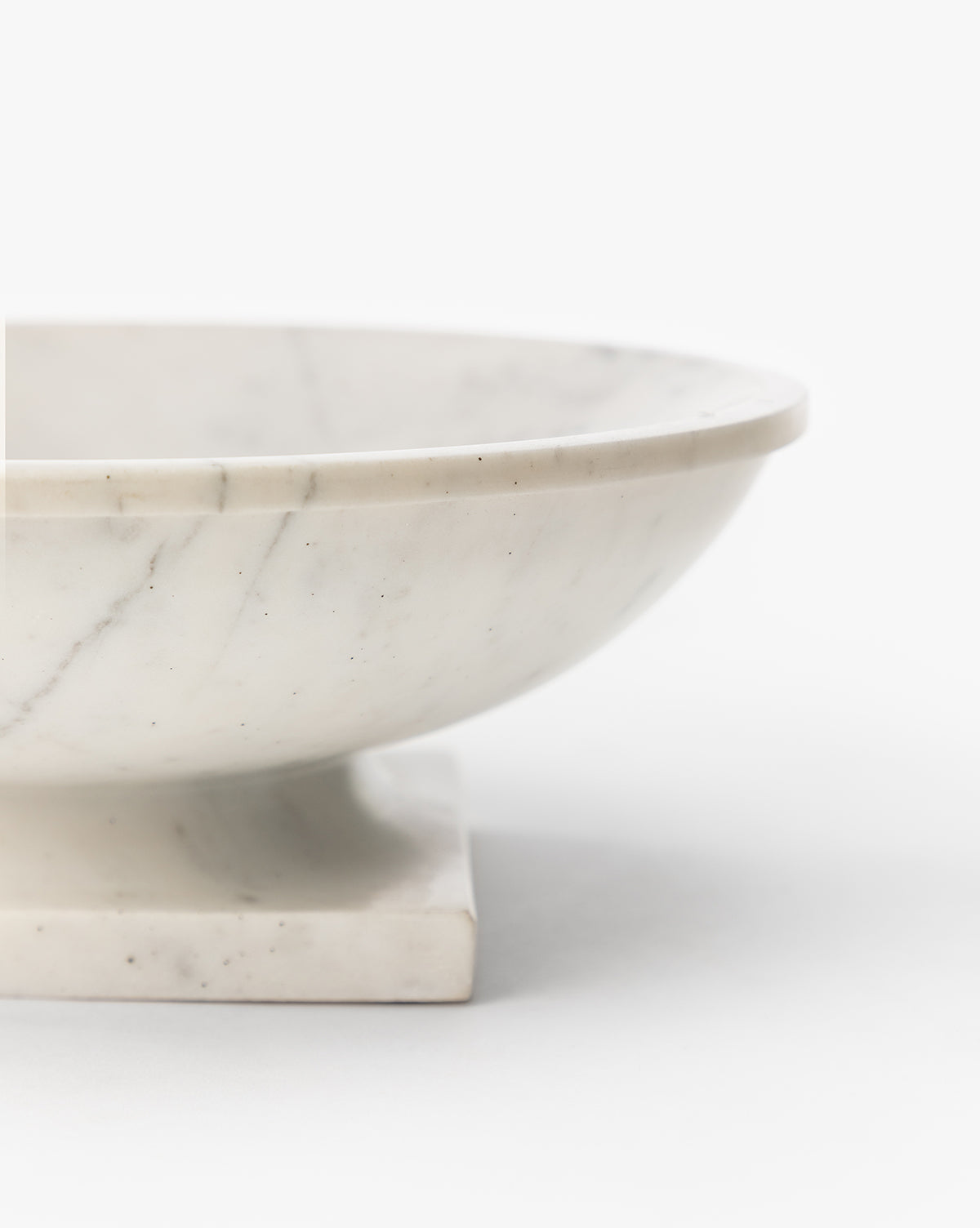 The Tayva Bowl, a sculptural white marble piece with subtle gray veining, is shown in close-up on a square base against a plain white background by McGee & Co.