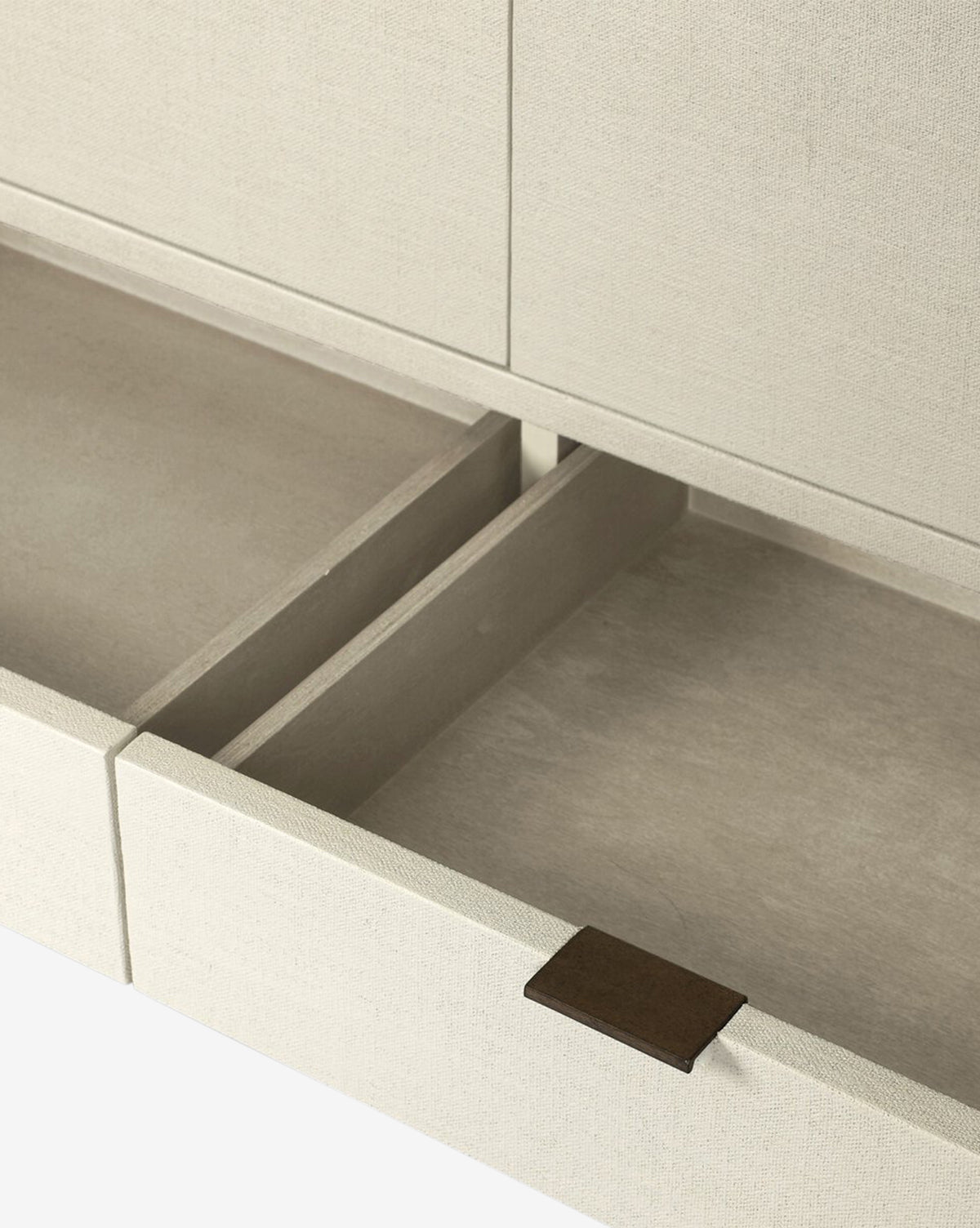 A close-up of an open beige drawer in the Thaddeus Cabinet, featuring a fabric-like texture, central divider, and brown rectangular pull tab—showcasing extra storage with modern classic style, by McGee & Co.