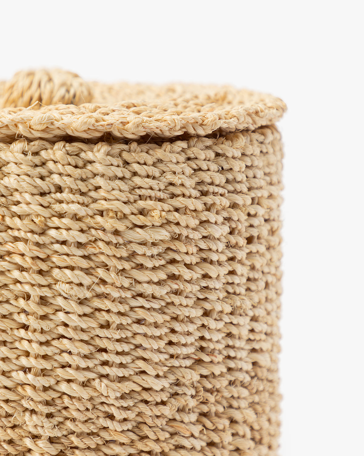 Close-up of the Thalia Woven Canister, crafted from natural, light-colored fibers in a braided pattern. Its cylindrical shape and organic texture make it perfect for stylish storage or bathroom counter decor. Shown against a white background.