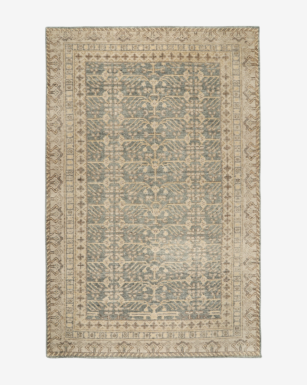 The Thames Hand-Knotted Rug features an intricate, symmetrical pattern in muted beige and blue tones, with a detailed border and central design—ideal for adding a touch of luxury to your home décor, by McGee & Co.