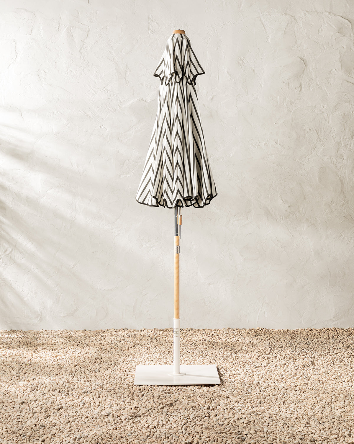 Patio umbrella shown closed black and white stripe to add style to outdoor spaces from McGee & Co.