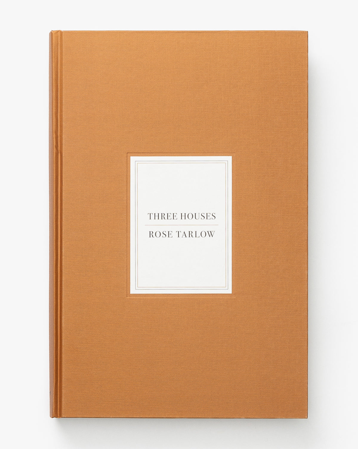 Three Houses is a hardcover design book by Rose Tarlow, featuring a tan cloth cover with the title centered on a white label, showcasing her signature timeless family home style.