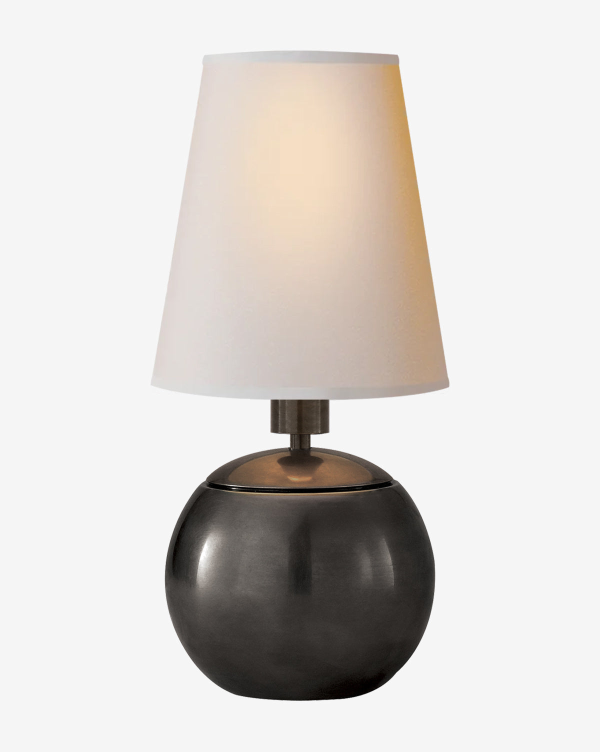 The Tiny Terri Accent Lamp, featuring a round, dark metallic base and a natural paper shade, is illuminated against a plain light background, by McGee & Co.