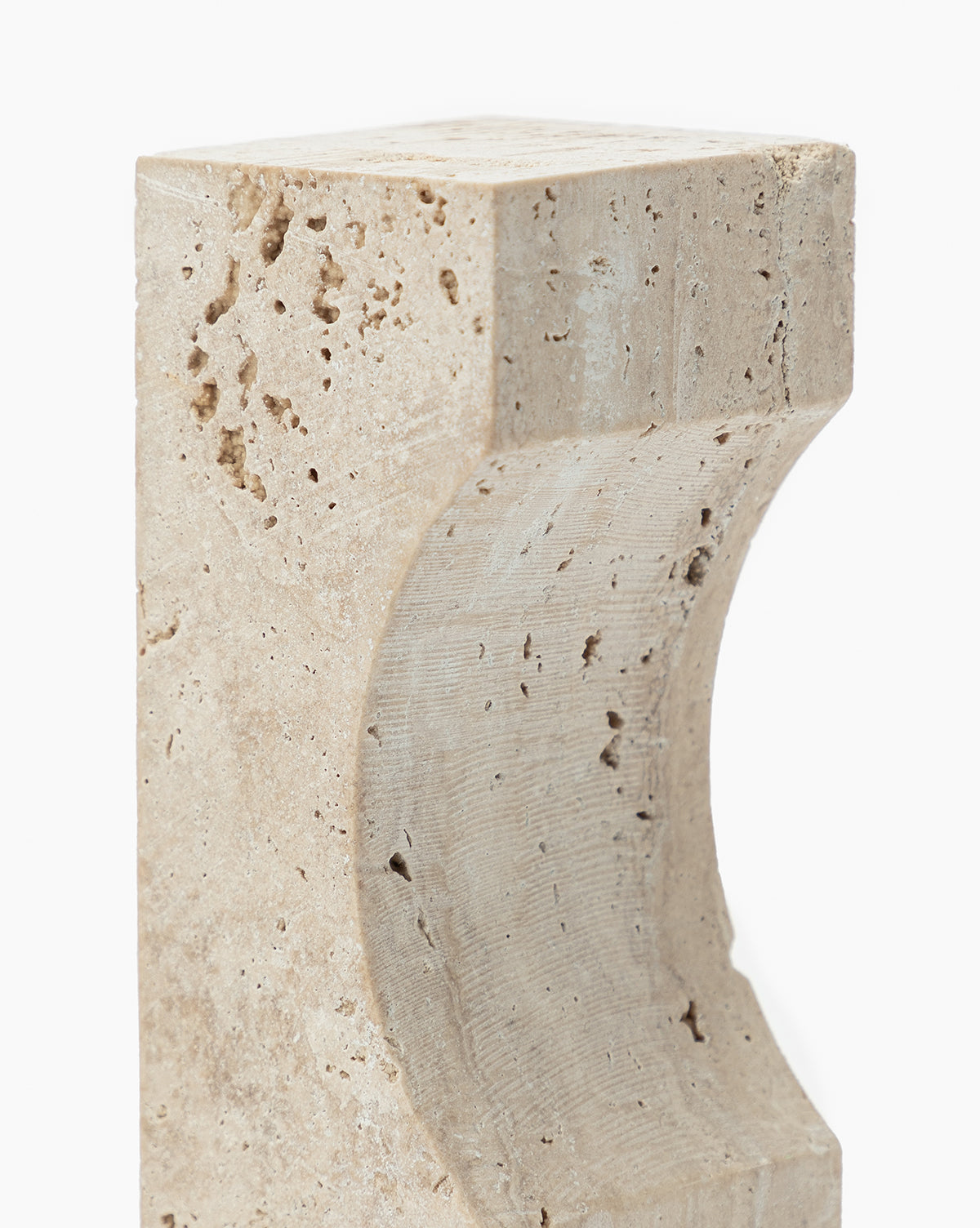 The Travertine Object is a beige, rectangular block featuring a smooth curved indentation and a porous, textured surface with natural holes—an eye-catching decorative accent.