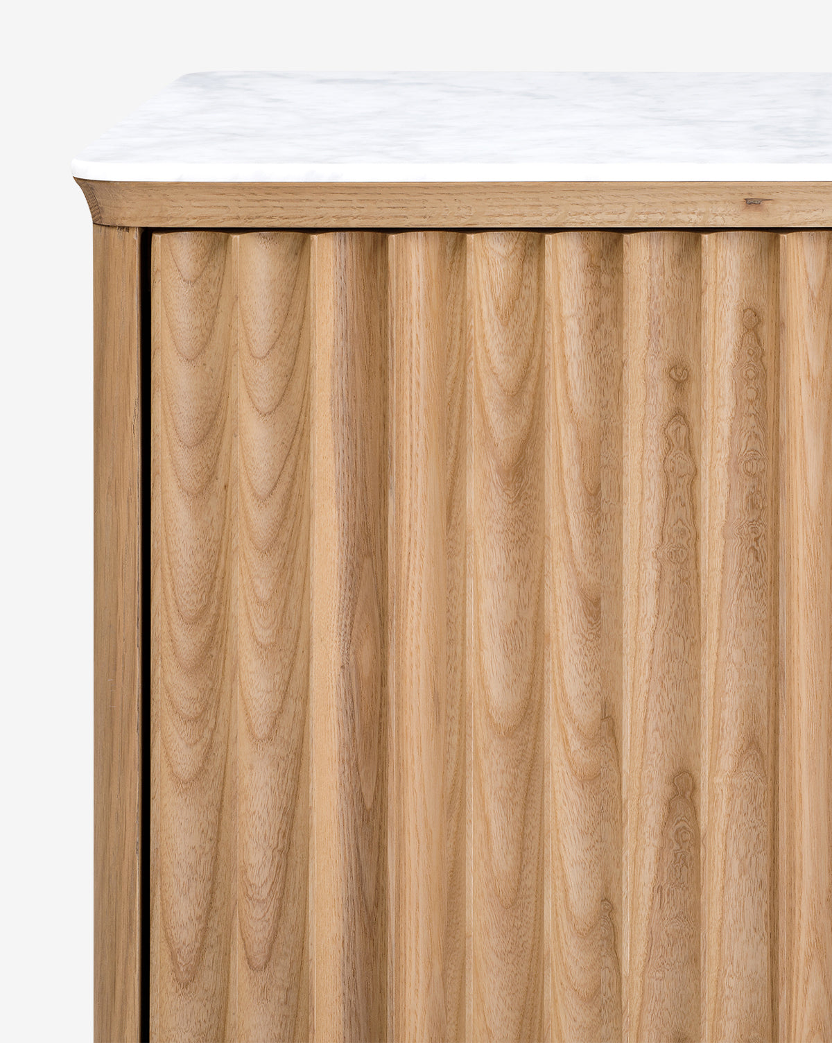 Close-up of the Vale Sideboard, showcasing vertical grooves, a white marble top, light natural oak grain, smooth edges, and elegant antique brass hardware, by McGee & Co.