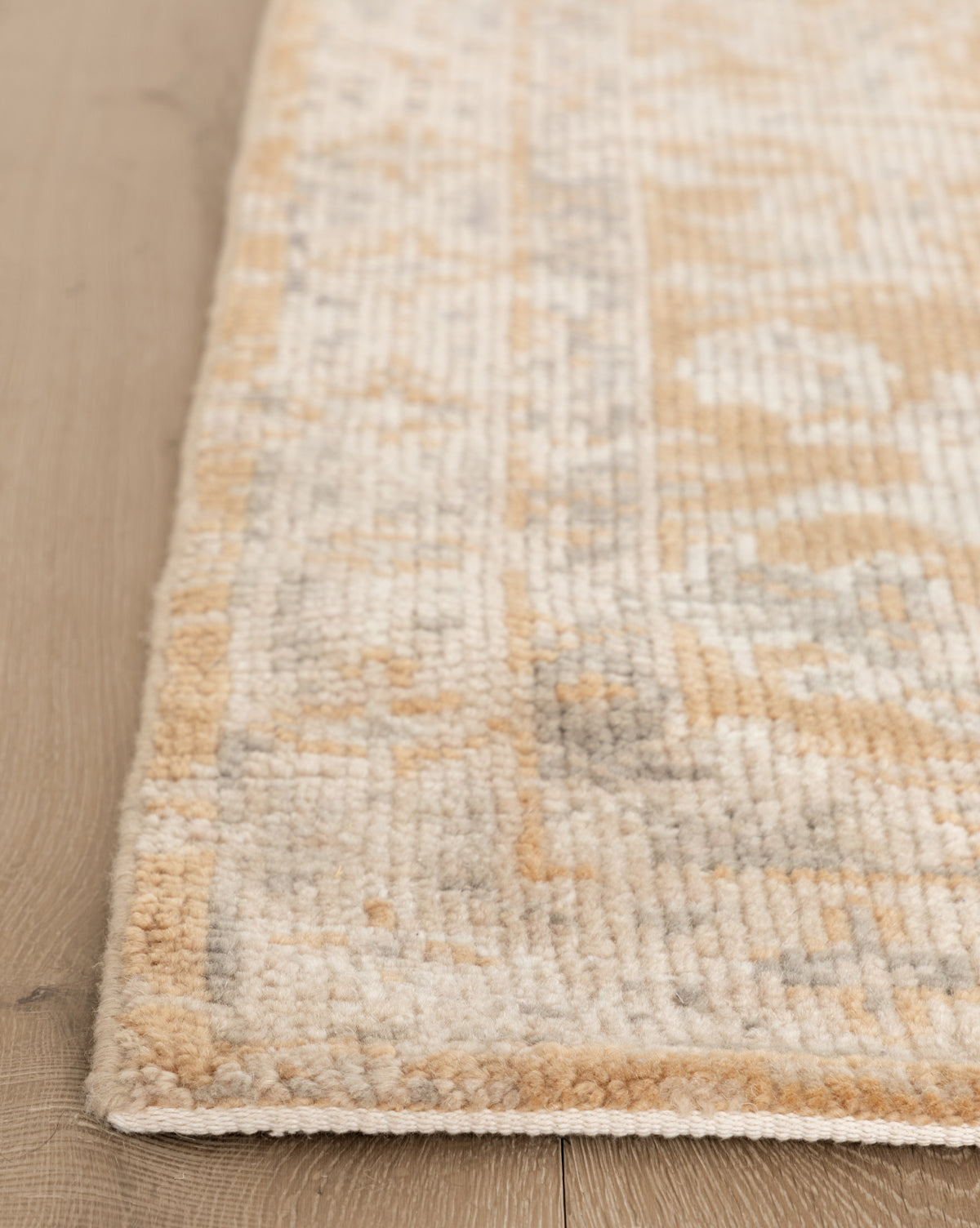 Close-up of the Vanderwood Hand-Knotted Wool Rug in beige and light brown on a light wooden floor, highlighting its soft wool texture and subtle geometric design, by McGee & Co.