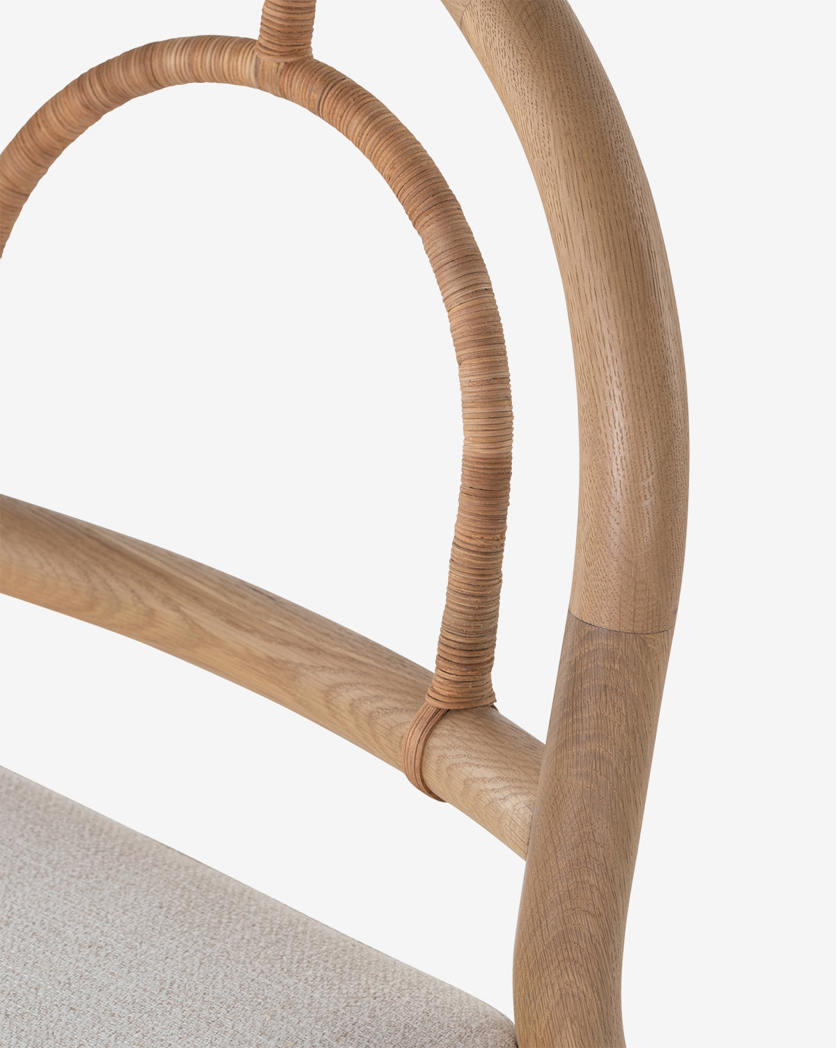 Close-up of the Vasco Dining Chair’s curved wooden backrest with wrapped detail and a light upholstered seat, highlighting its artistic appeal against a white background by McGee & Co.