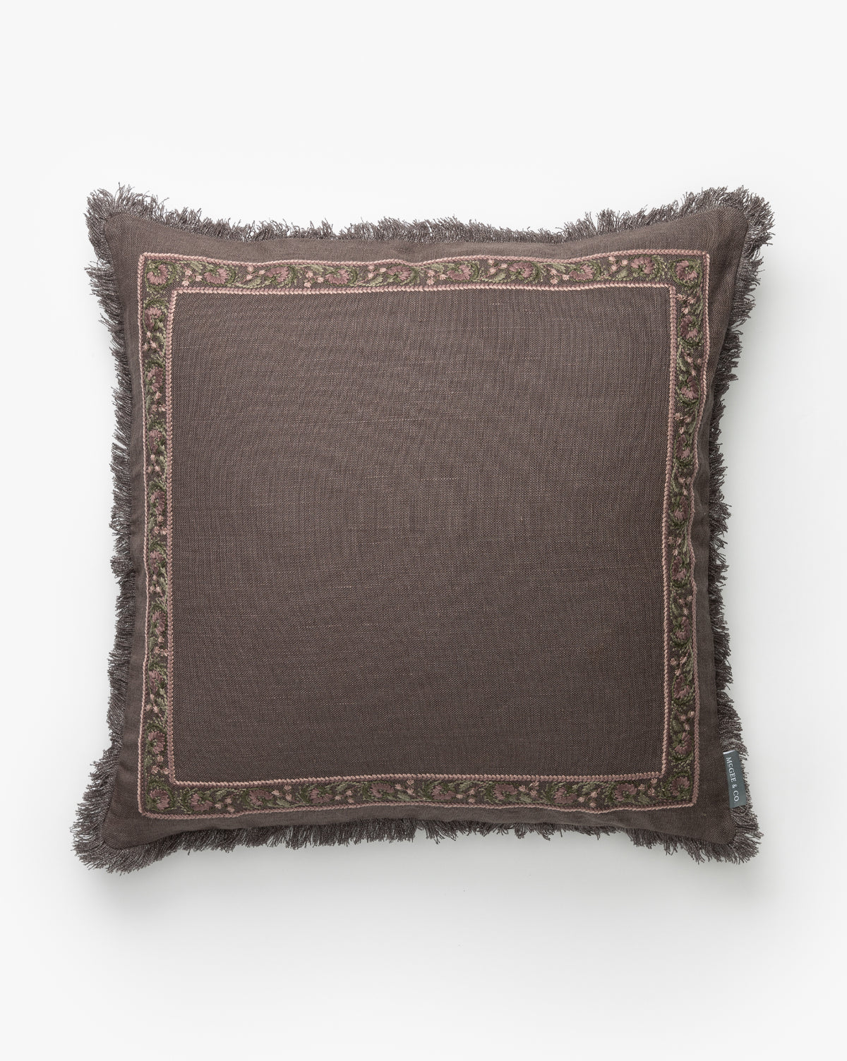 Square brown linen pillow with fringed edges and a soft pink and green embroidered floral border, shown on a white background. Pair it with the Venetia Pillow Cover for a stylish accent in your space, by McGee & Co.