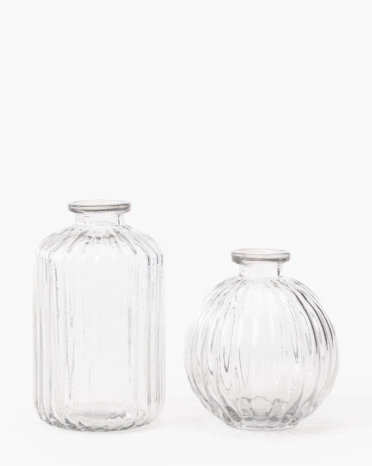 The Verlice Glass Round Vase features mouth-blown clear glass with vertical ribbed patterns, a narrow opening, and a round shape—ideal for decorative vignettes on any surface.