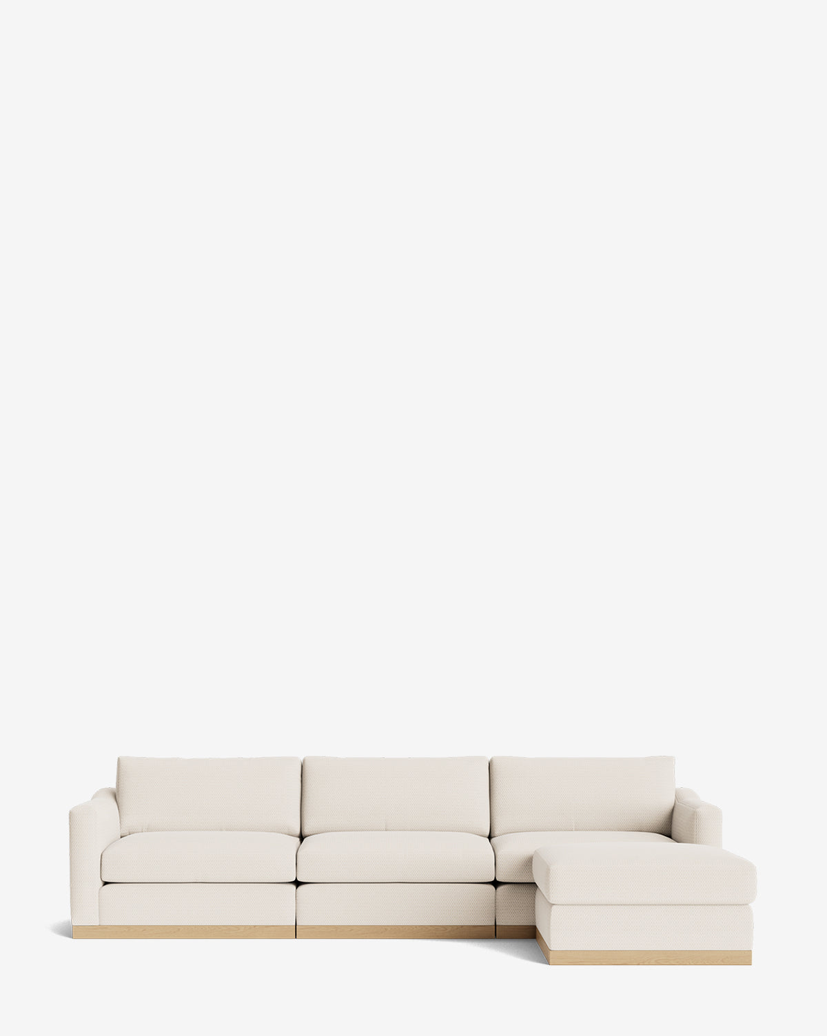 The Vernon Modular Sofa with Ottoman 121 is a modern, light beige sectional with three seats, a right-side chaise lounge, boxy cushions, and a low wooden base, shown against a plain white background by McGee & Co.