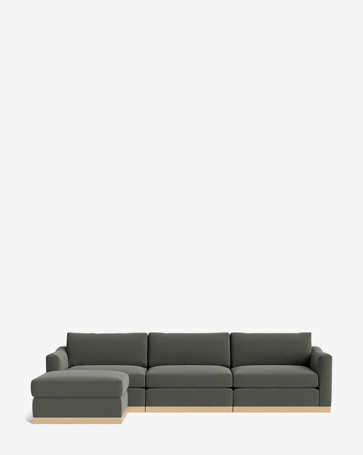 A modern dark gray Vernon Modular Sofa with Ottoman 121, featuring a left chaise and light wood base, is set against a plain white background. This customizable fabric sofa offers sleek style and flexible comfort by McGee & Co.