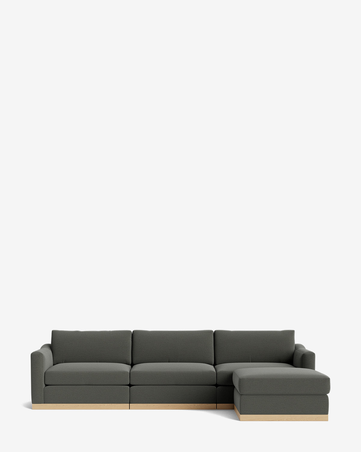 The Vernon Modular Sofa with Ottoman 121 is a modern dark gray sectional featuring wide cushions, low backrests, a right-facing chaise, and ottoman. It has a minimalist design with a light wood base and no visible legs for a sleek look by McGee & Co.
