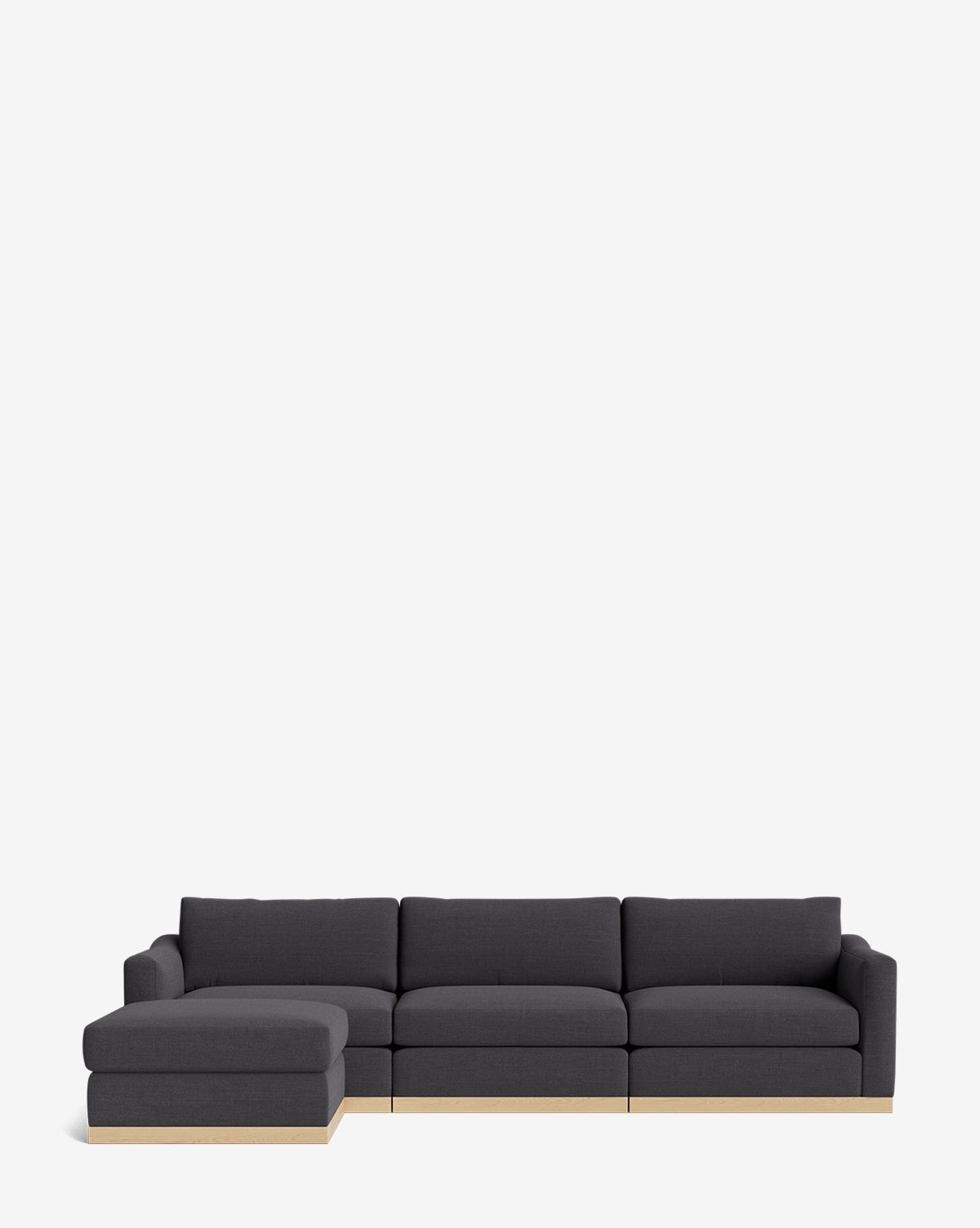 The Vernon Modular Sofa with Ottoman 121 is a modern dark gray sectional with a left chaise and light wood base, shown on a plain white background. This customizable fabric sofa offers stylish versatility for contemporary spaces, by McGee & Co.