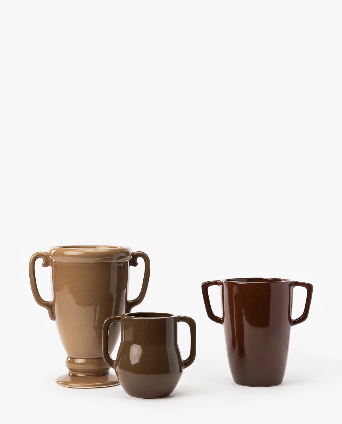 Three Victoire Vases in brown ceramic, each varying in shape and size, are arranged side by side on a white background, with the tallest vase on the left and the smallest earthenware piece in the center, by McGee & Co.