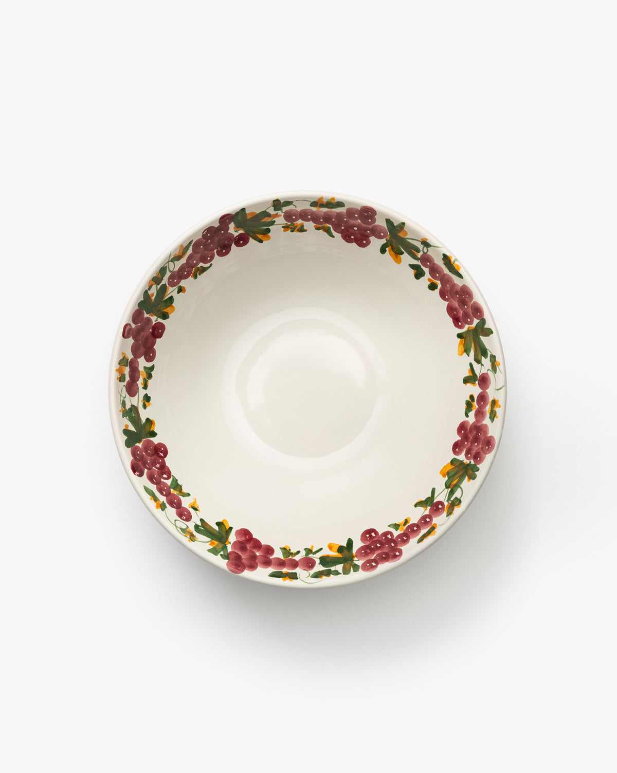 The Vine Large Bowl is a handmade ceramic piece with a decorative rim of red berries, green leaves, and a grapevine motif, seen from above on a plain white background—ideal for enhancing any table setting, by McGee & Co.