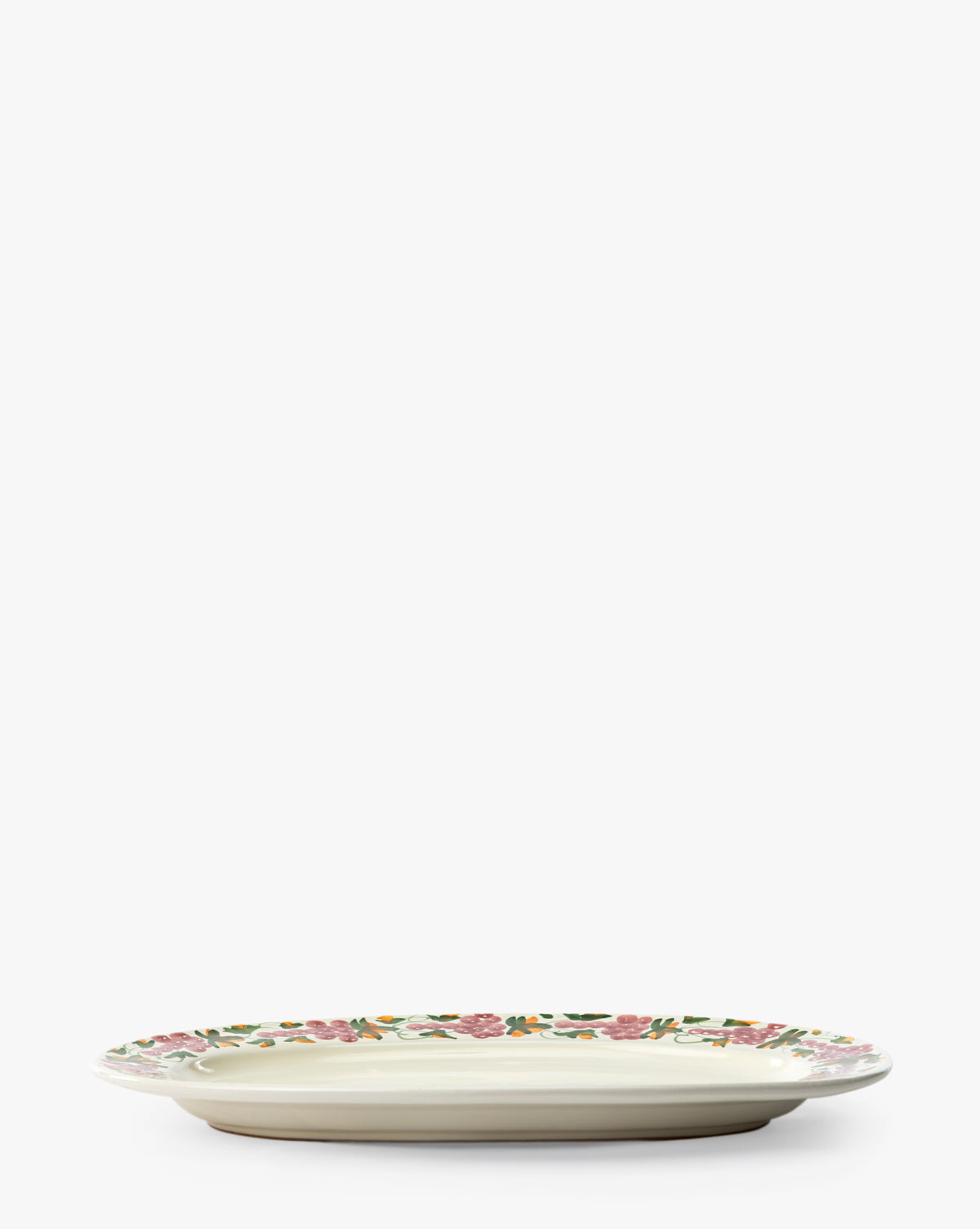 The Vine Serving Platter is a round handmade ceramic piece featuring a white base and a green and pink floral grapevine motif around the rim, displayed against a plain white background, by McGee & Co.