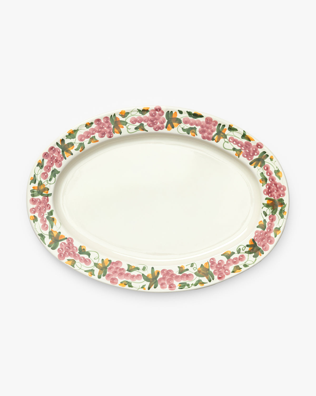 The Vine Serving Platter is an oval, handmade ceramic tray with a cream center and a hand-painted grapevine rim featuring pink grapes and green leaves, by McGee & Co.
